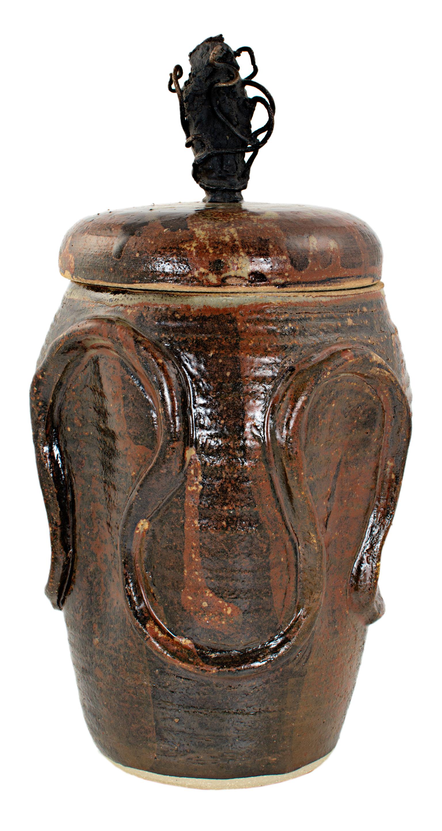 "Cover Jar w/ Grapevines" is a stoneware and bronze vessel by Ernst Gramatzki. 

10 1/2" x 5 3/4" 

Ernst Gramatzki is a world renowned artist, sculptor, potter, painter and poet. Some of his work is in the Smithsonian Institute in D.C. as well as