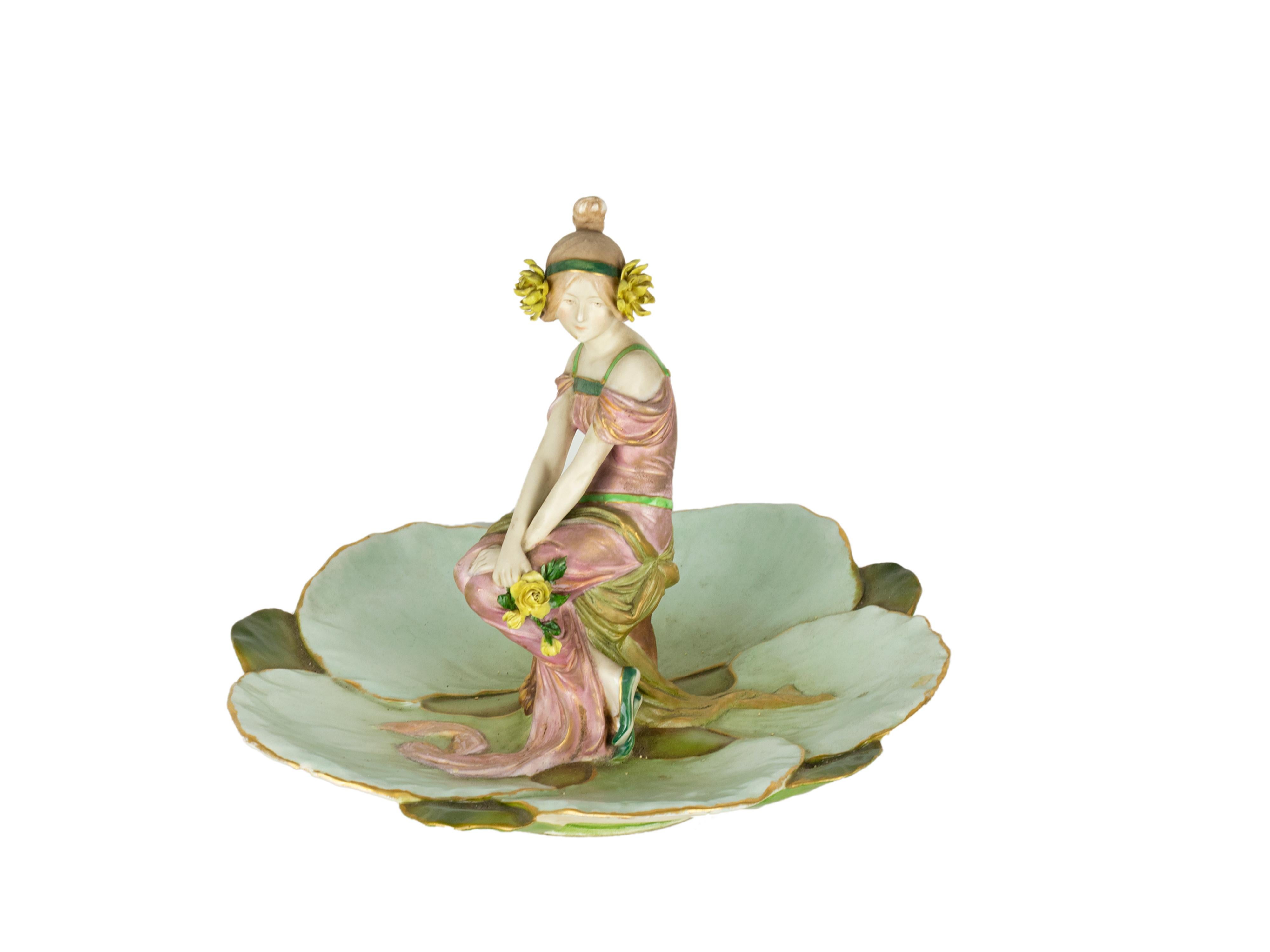 Uno straordinario vassoio con statuetta in porcellana dipinta a mano in stile Secessione di Ernst Wahliss con un'elegante fanciulla seduta affiancata da un giglio verde.
Prodotto a Teplitz (Austria) 
Circa 1891
