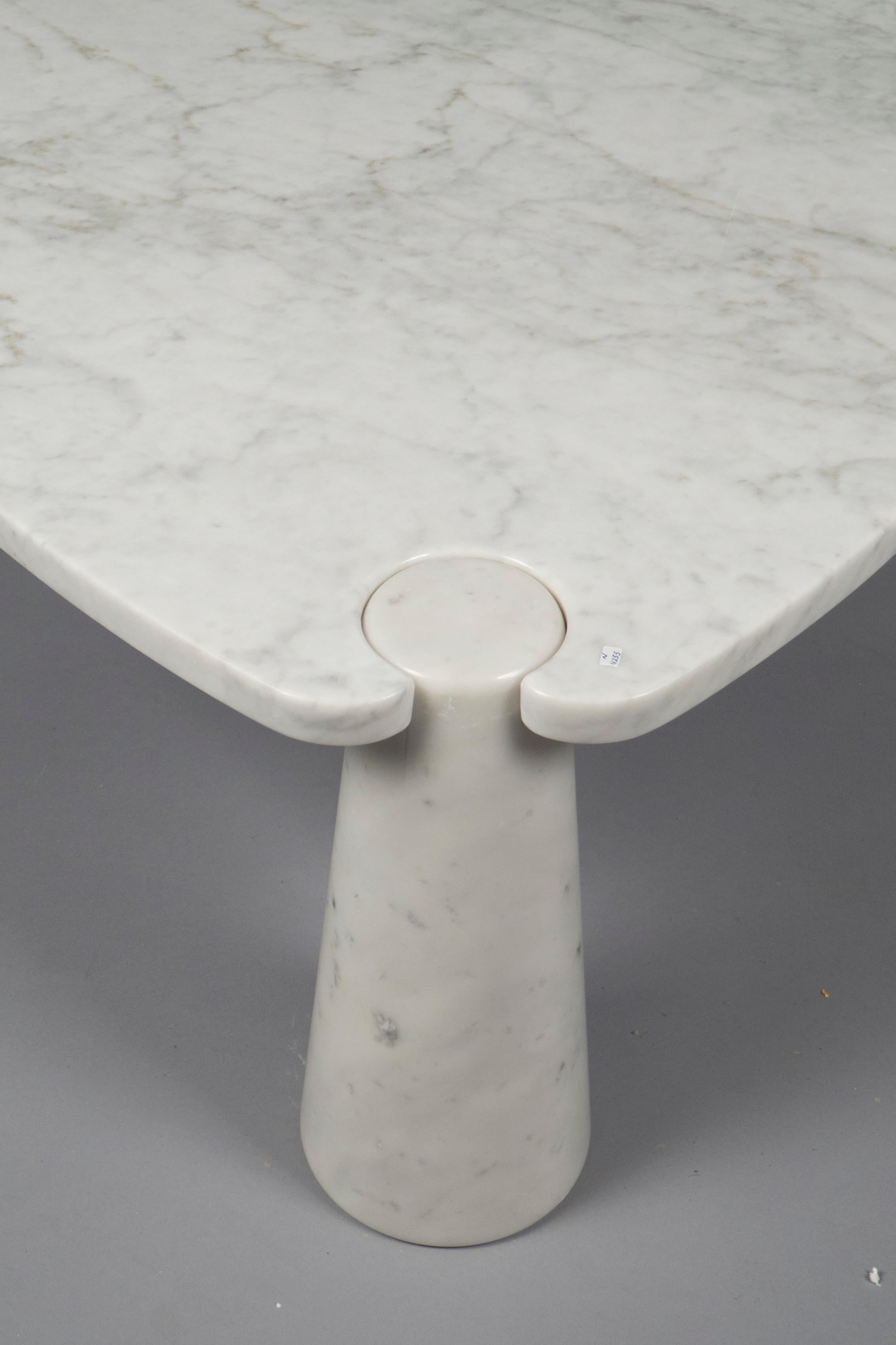 Triangular coffee table of a white and grey veined marble top, which rests on three cone shaped legs of the same material. Eros series.