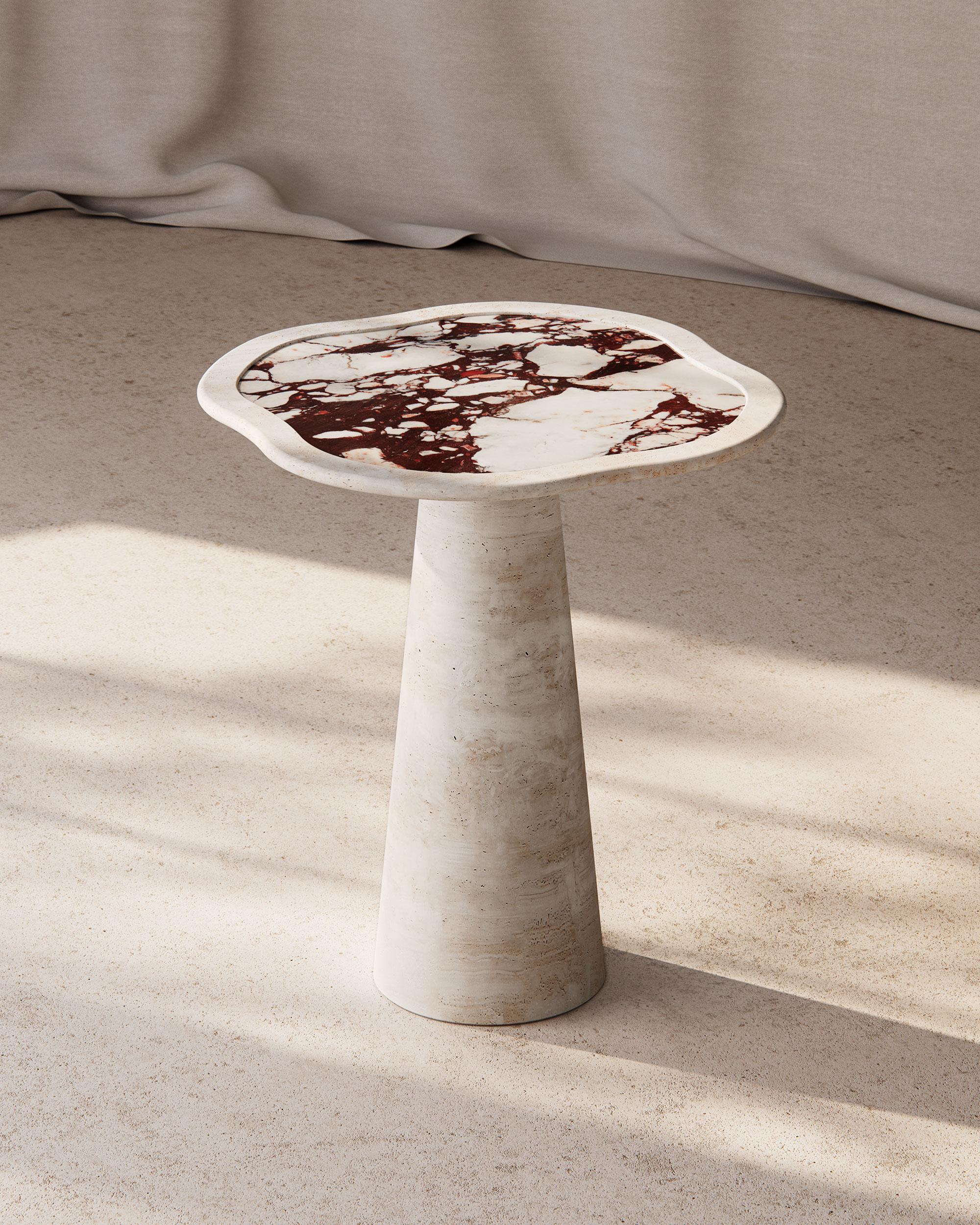 The Cupid Foyer Table by The Essentialist, elegantly crafted from Italian Ivory Travertine and adorned with a Calacatta Viola inlay, is an object d'art that strikes an alluring harmony between form and material. Its organic silhouette, graced with