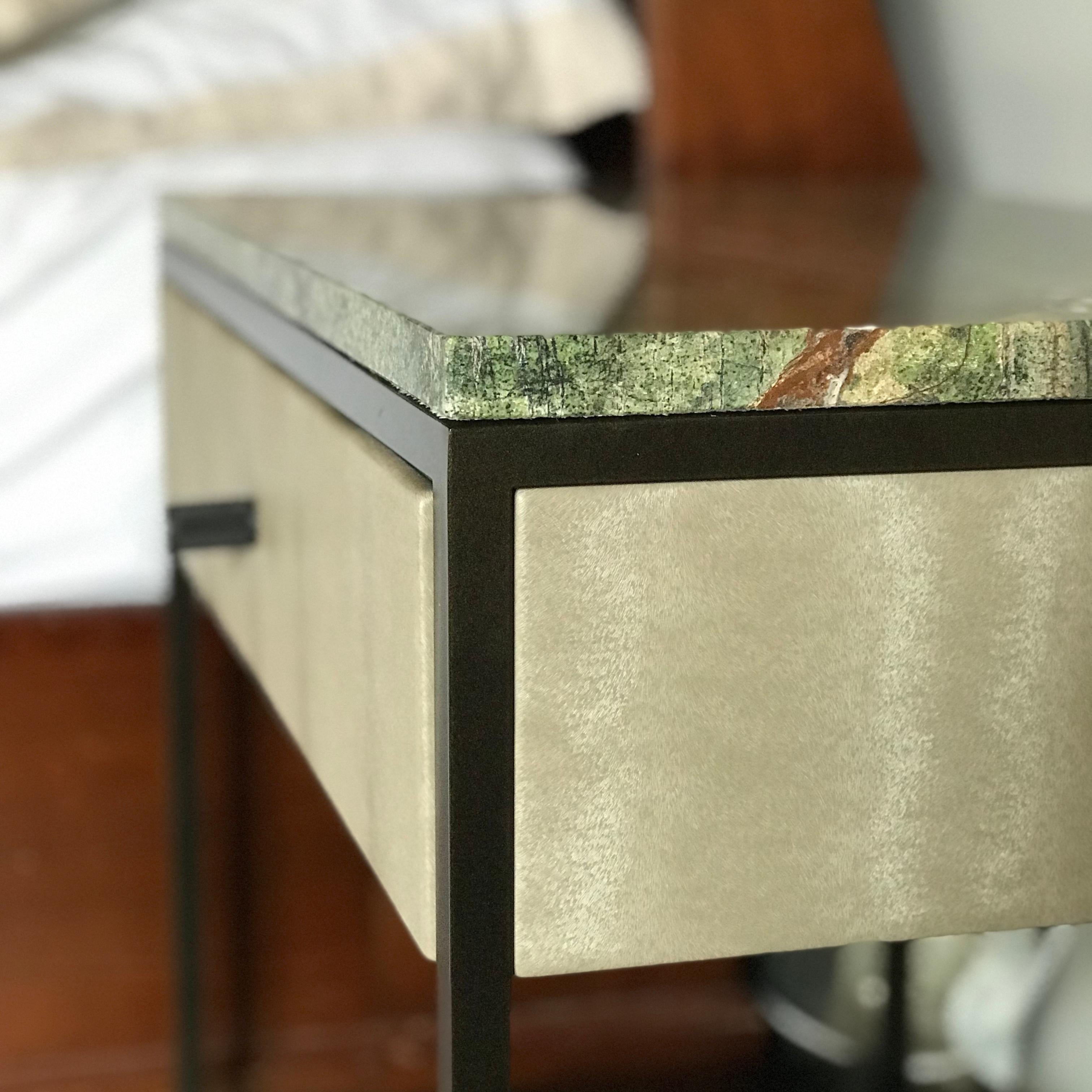 The Eros Bedside Table is a stylish and functional piece of furniture that combines both form and function. The table features a sturdy steel base and a luxurious Marble top. The drawer of the table is upholstered in one of two innovative materials