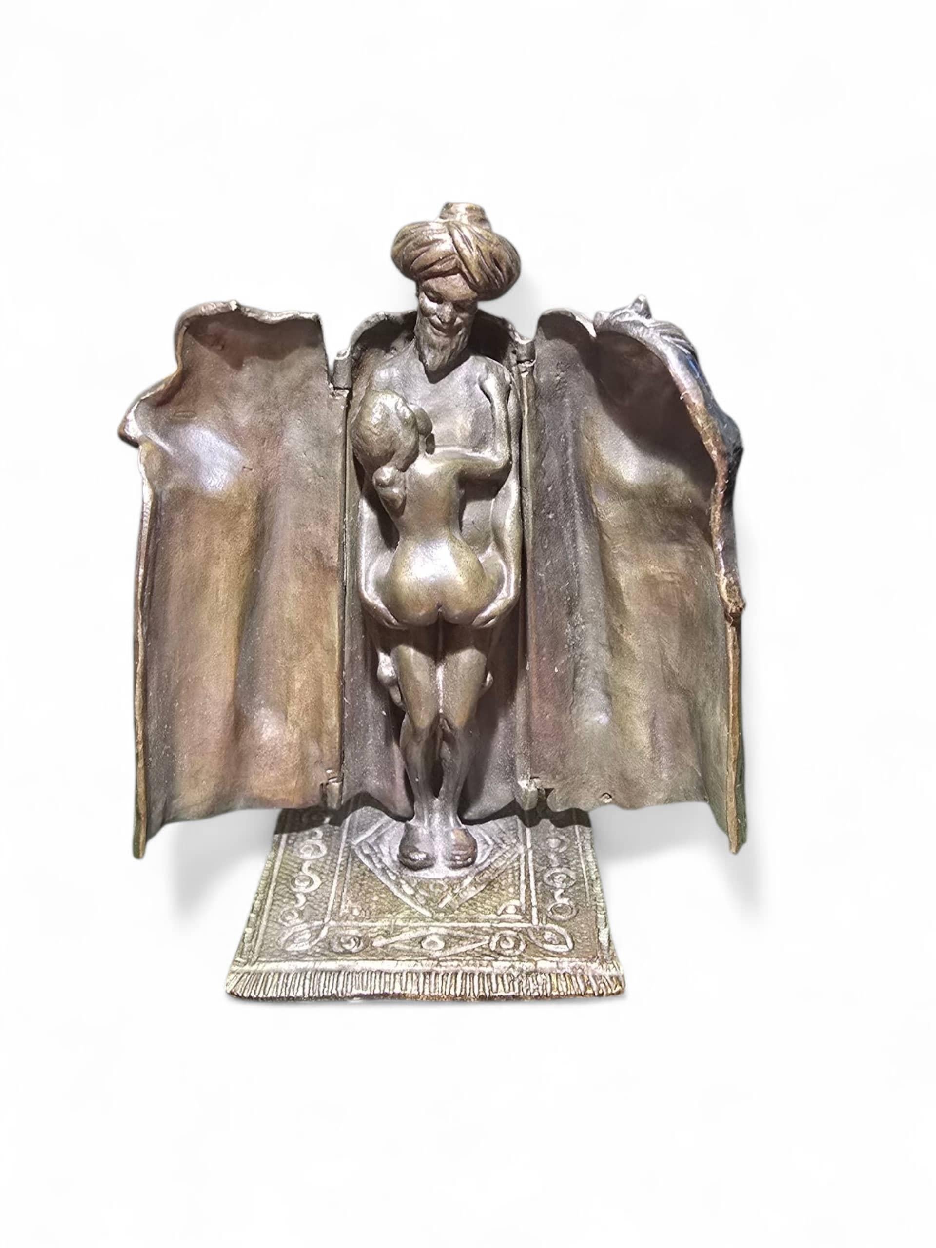 Erotic Bedouin Bronze By Franz Bergmann
This Austrian  bronze figure by Franz Bergmann hides a secret. A Bedouin man stands atop a vibrantly patterned carpet stroking a cat. But unlatch his robe and his spring-loaded arms open to reveal that the man
