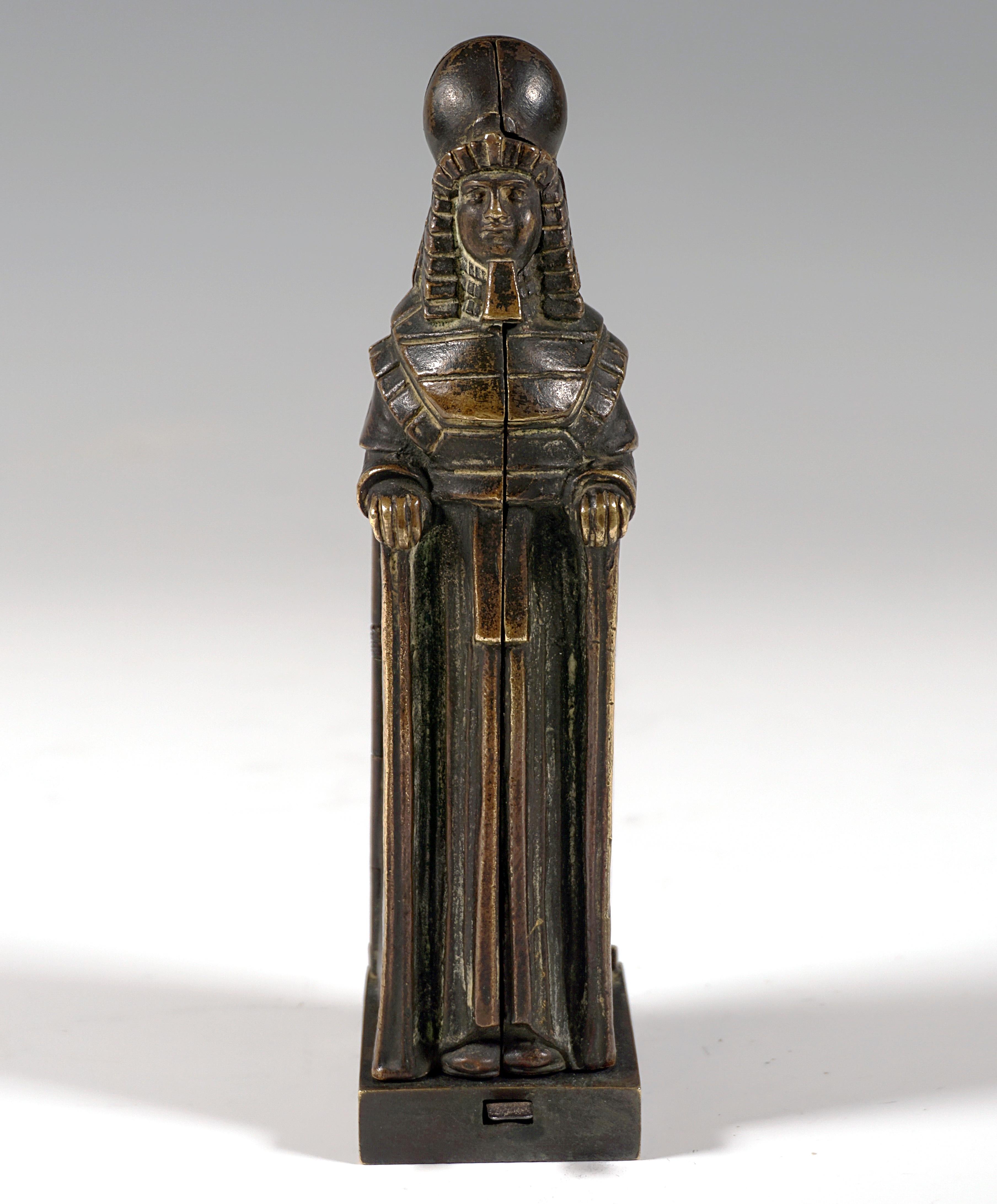 At first glance an upright Egyptian sarcophagus, which opens to both sides when pressure is applied to a small lever on the front of the base, revealing an upright nude young woman with arms crossed on her chest, the side panels are attached to the