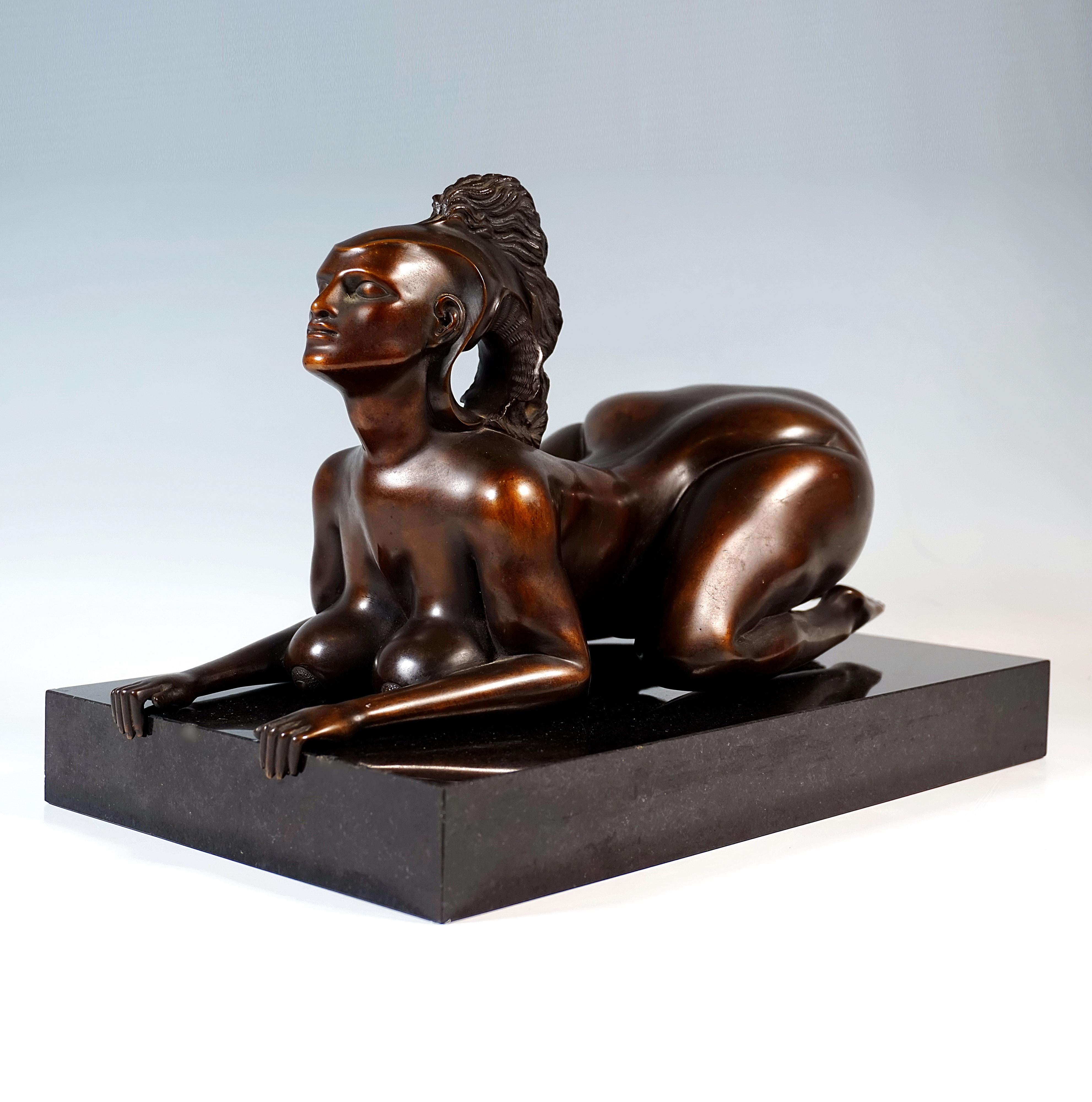 Golden brown patinated figure of a crouching female nude in the form of a sphinx with an imaginative helmet, freely resting on  rectangular, polished granite base. Cast by Venturi Arte, Bologna. Published by The Hilliard Collection GmbH, Munich.

On