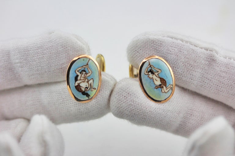This striking pair of cufflinks feature oval front faces adorned using colorful enamels to depict an erotic scenes split in the two faces. 
These two different vignettes are one-of-a-kind, exquisitely rendered mini-paintings mounting in 18 karat