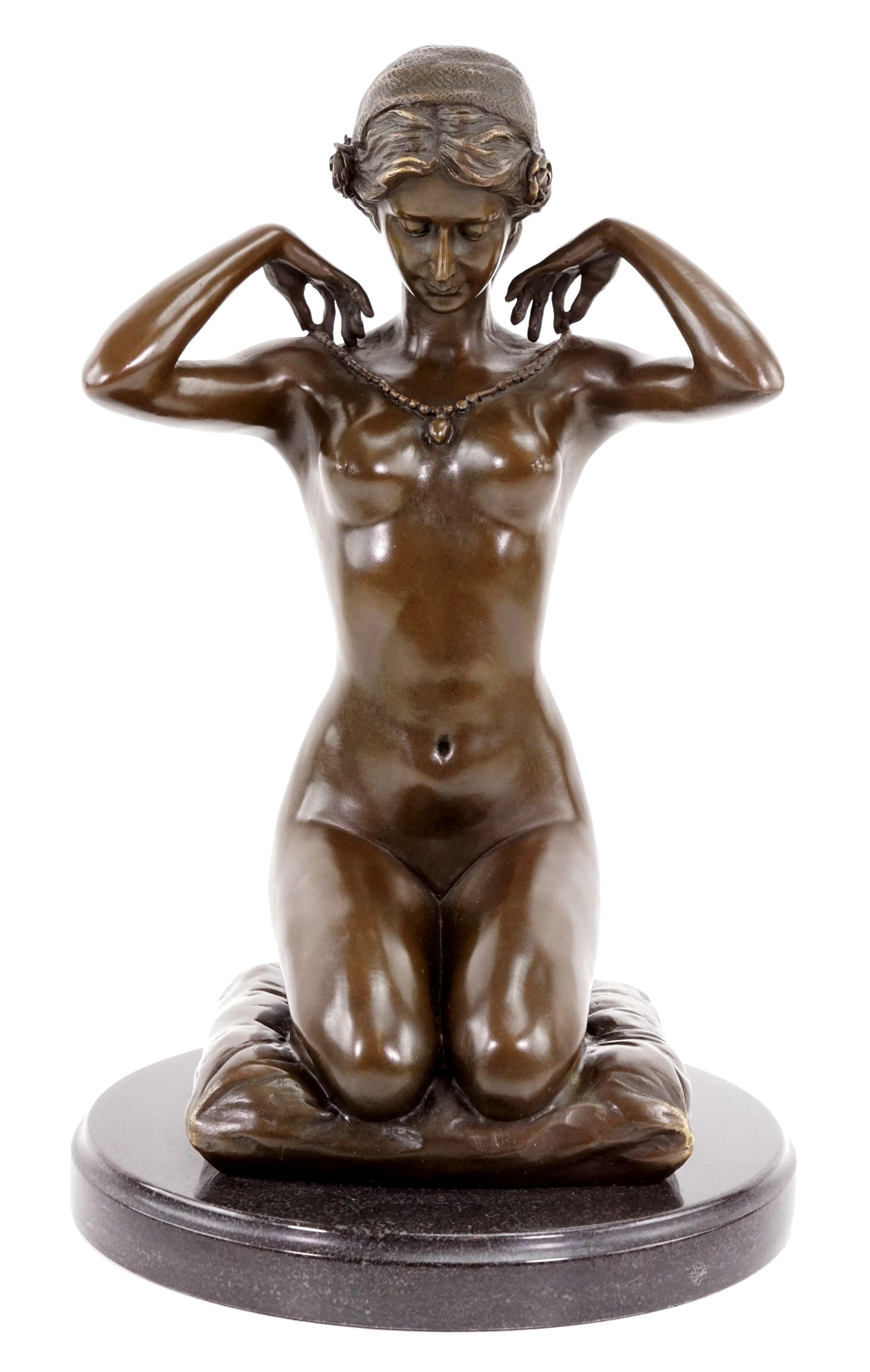 Esta estatua erótica desnuda al estilo de la escultura Art Nouveau representa a una mujer desnuda arrodillada ajustándose un delicado collar, combinando sensualidad y gracia introspectiva en líneas fluidas y naturales típicas del estilo Art