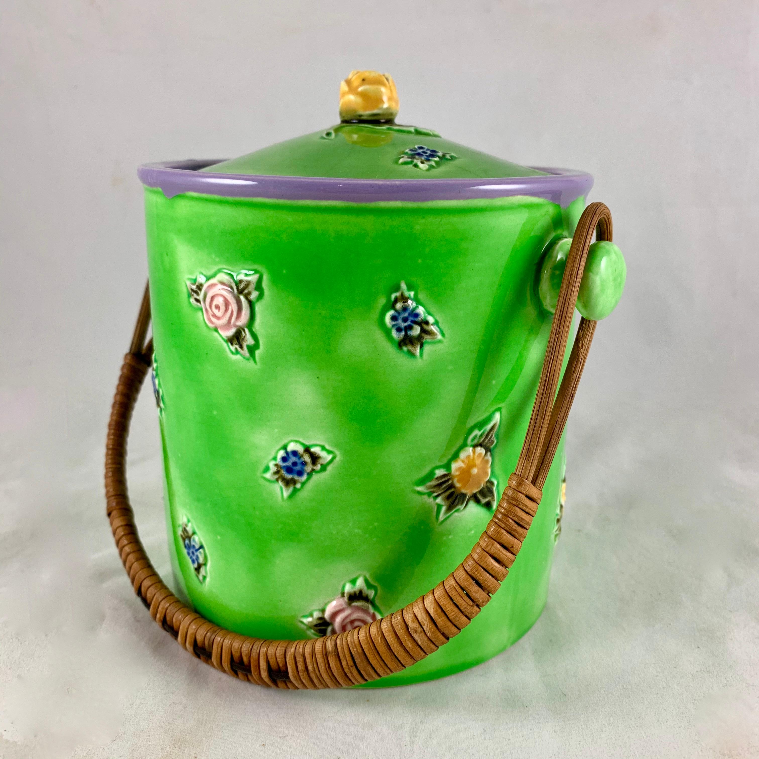 A charming, brightly glazed biscuit barrel with a rattan handle, made in Czechoslovakia for Erphila importers, circa 1918-1920.

The barrel and lid are hand painted in an incredible spring green and dotted with flowers and leaves glazed in pink,