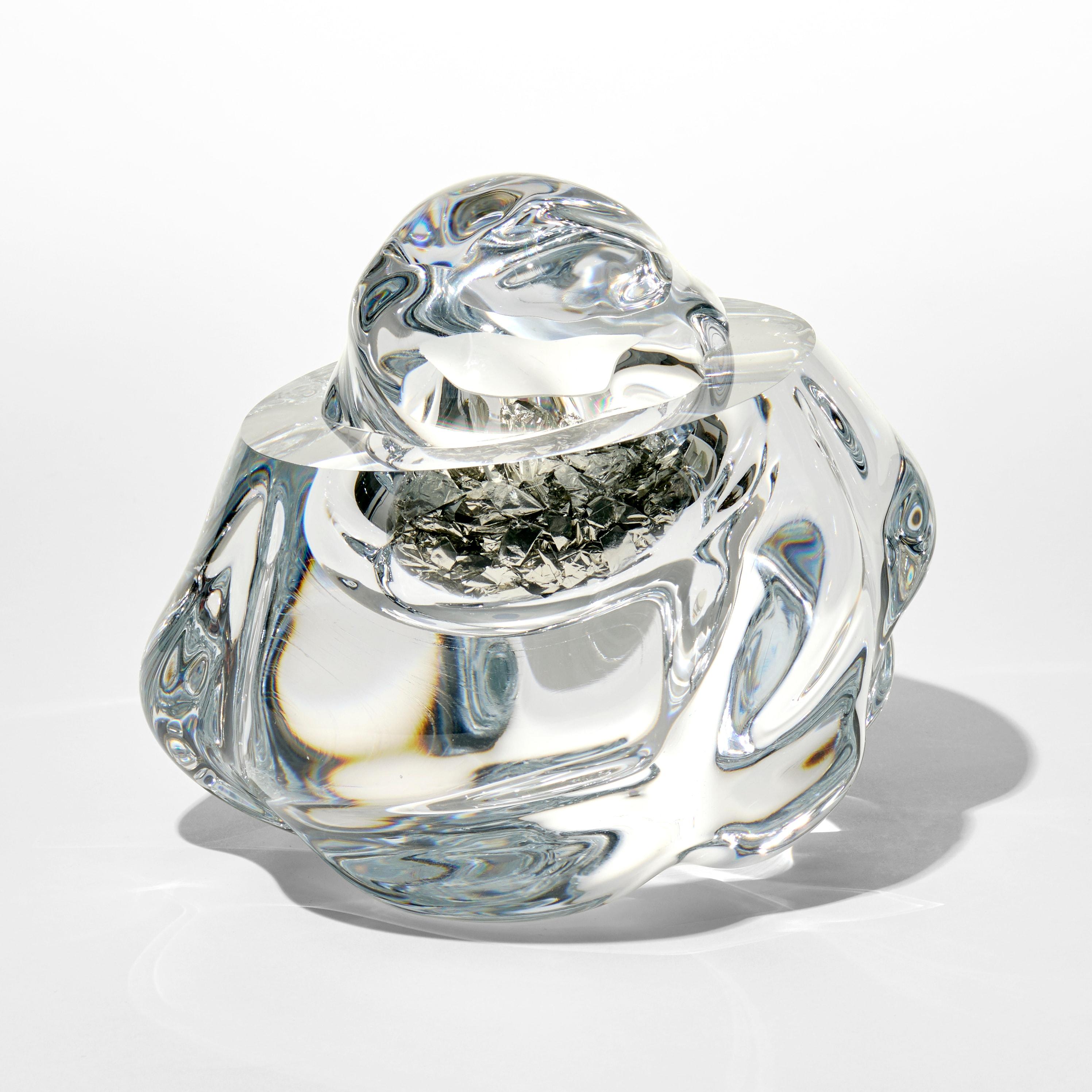 'Erratic with Tin Leaf' is a handblown and cut glass sculpture created by the British artist, Anthony Scala.

The geological term 'erratic' refers to a stone or boulder that differs to its surrounding rock, that is believed to have been displaced