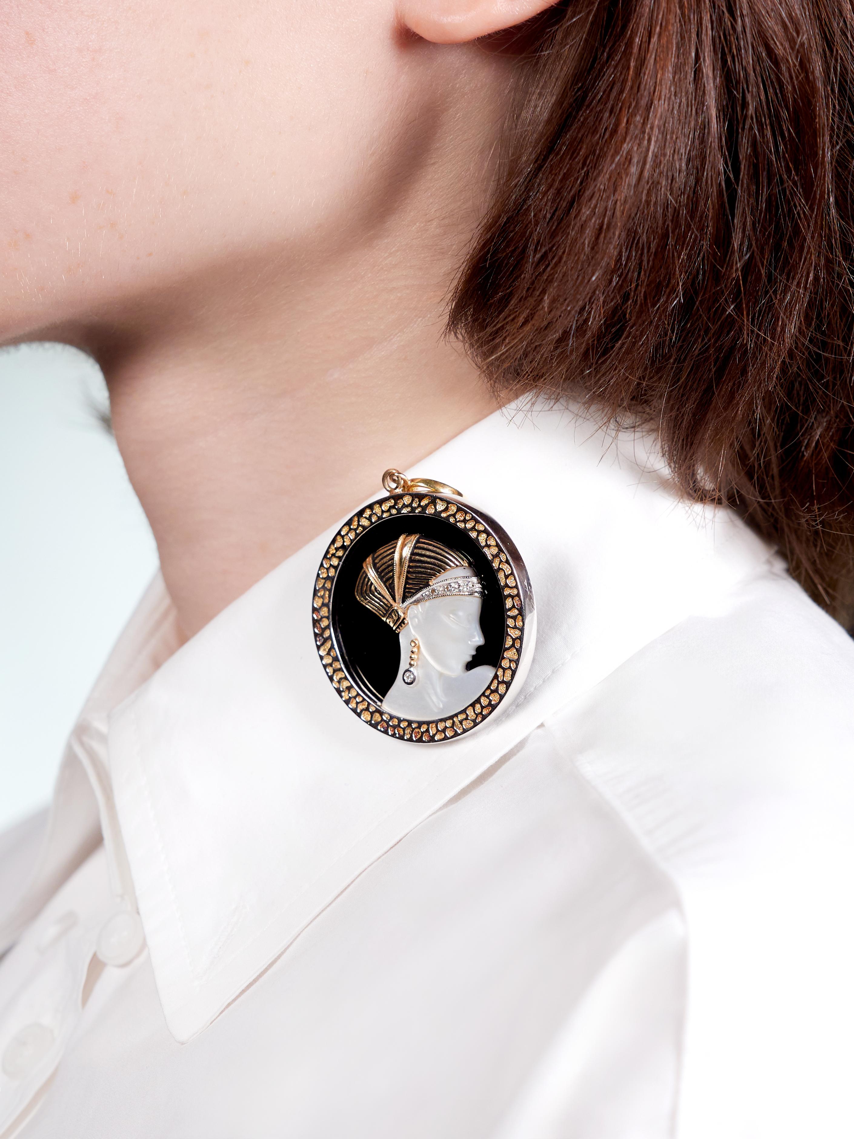 Designed as a disk shaped pendant depicting a woman wearing headdress in profile
Centering a 45.0 mm round onyx tablet bezel set with a highly rendered overlay
Opaque glossy black - overlay depicts of a woman carved from mother-of-pearl
Translucent