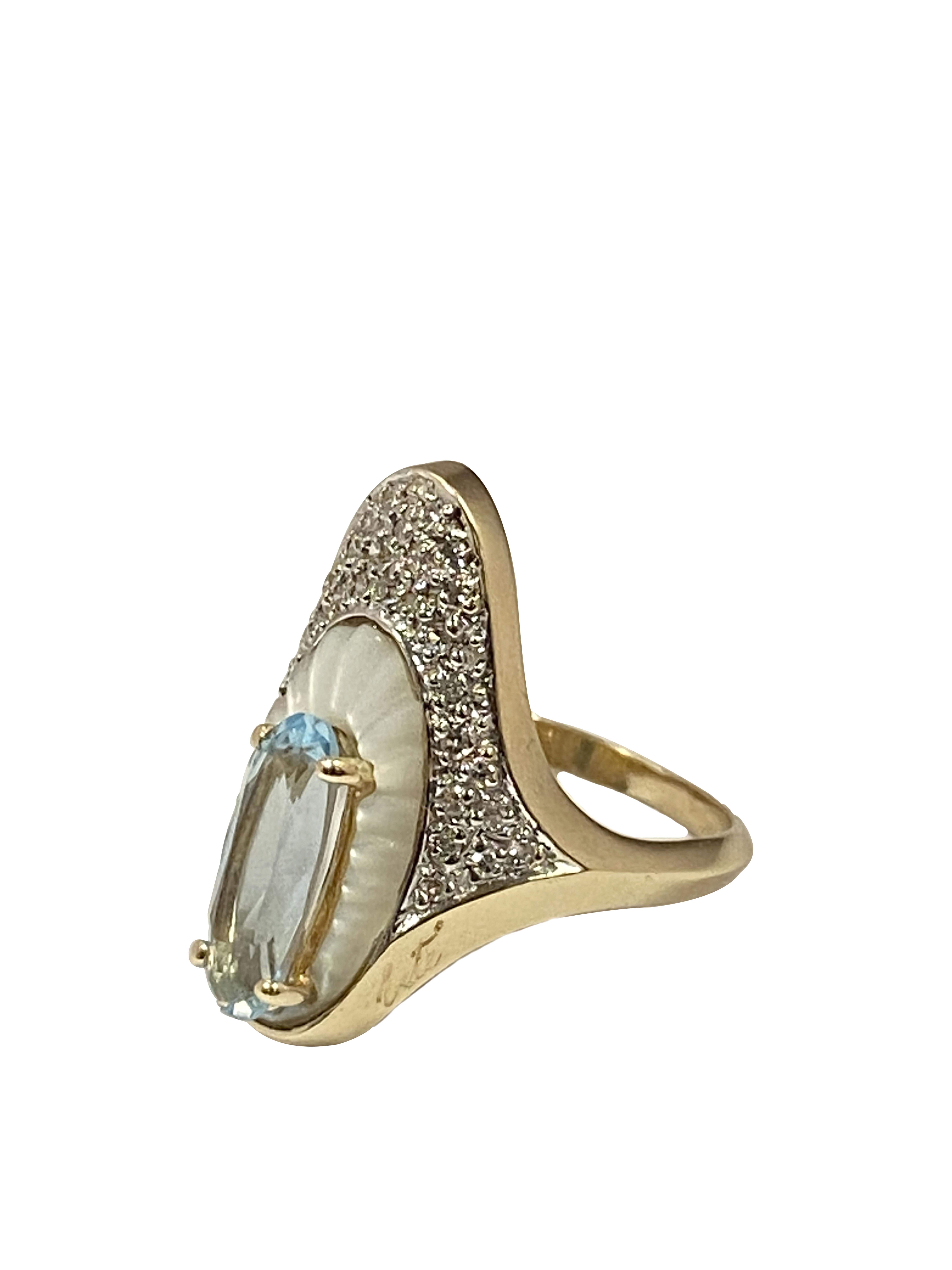 Circa 1980s Erte Alouette 14k Yellow Gold Ring in the famous Erte Art Deco style the ring measures 7/8 inch in length X 5/8 inch wide, centrally set with an oval Blue Topaz set on top of a carved Mother of Pearl and further surrounded by Round