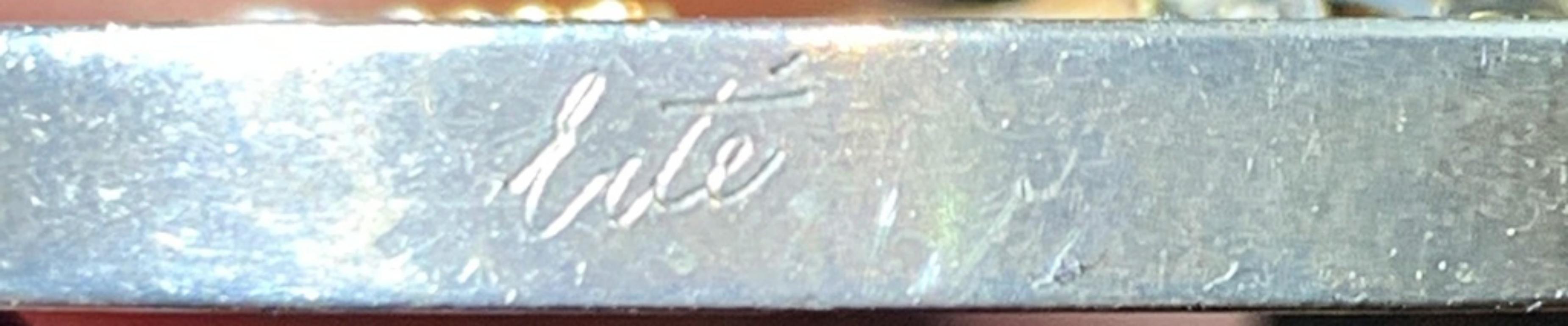Erte 
L'incanto dell'amore, 1980 ca.
Spilla in argento sterling con oro 14 carati, sfondo in onice e testa di donna in madreperla con (4) diamanti tondi taglio brillante.
1 1/2 di diametro
Edizione limitata di 100 esemplari (non numerati)
La firma