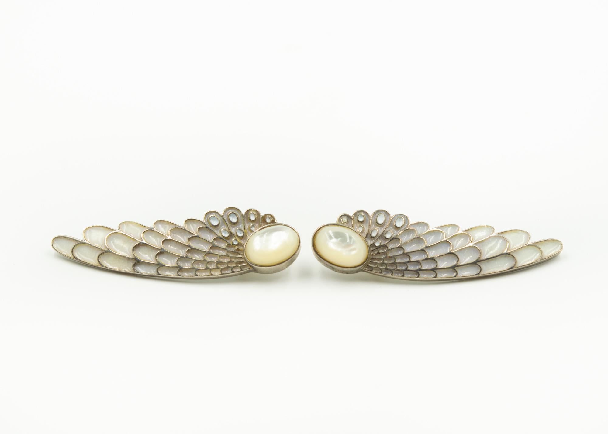  ERTÉ  sterling silver earrings designed in a winged pattern with white enamel, and two mother-of-pearl oval cabochons measuring approximately 9 x 13 millimeter.  One earrings is signed ©CFA Sterling and the other has ERTe etched into it with the