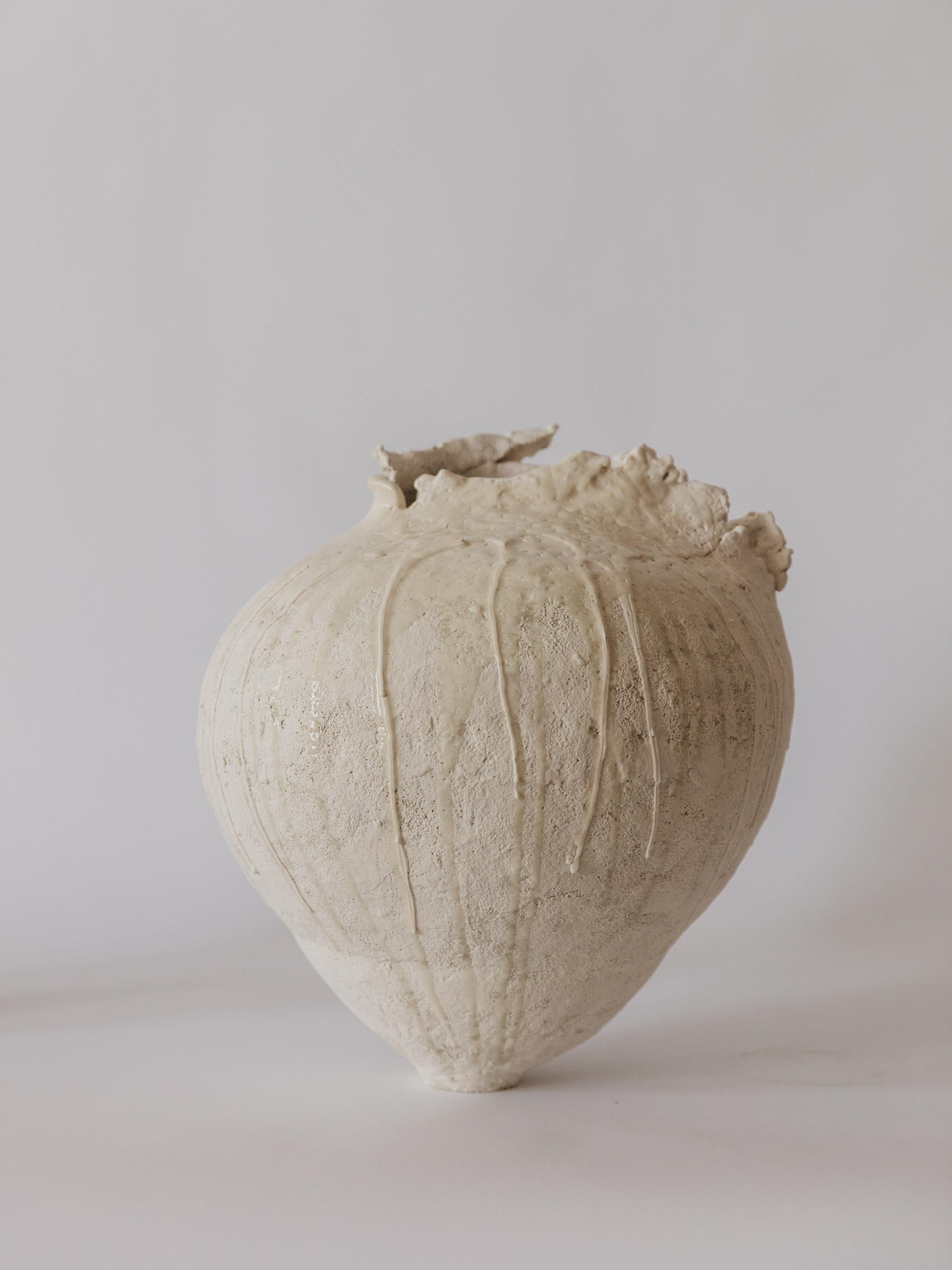 Este recipiente escultórico de Ilona Golovina está fabricado a mano con gres blanco y acabado con texturas en capas y detalles fluidos de esmalte. La forma es bulbosa y, a la vez, firme, con un borde asimétrico y desgarrado que parece a la vez