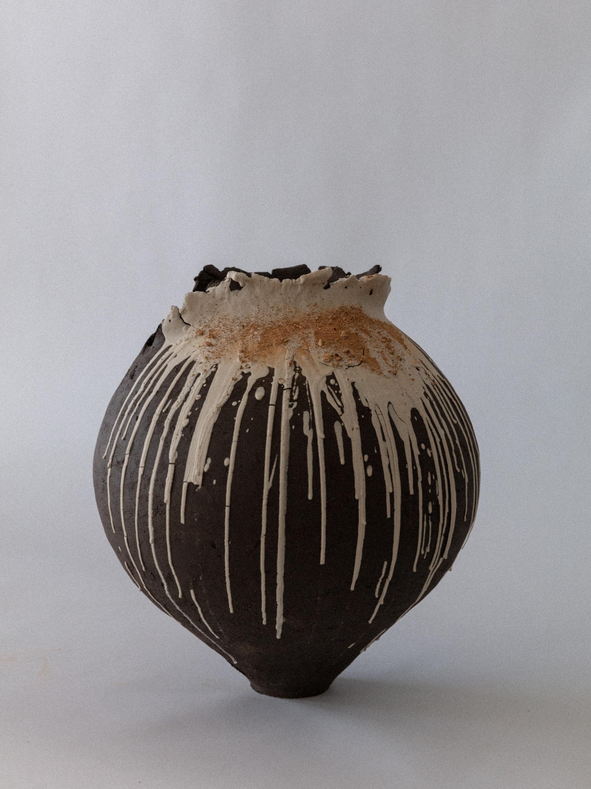 Questo vaso scultoreo di Ilona Golovina è costruito a mano in gres scuro e presenta un bordo asimmetrico e drammatico con stratificazione. Il corpo si erge in una corona frastagliata, simile a un cratere, che sembra quasi vulcanica: una rottura