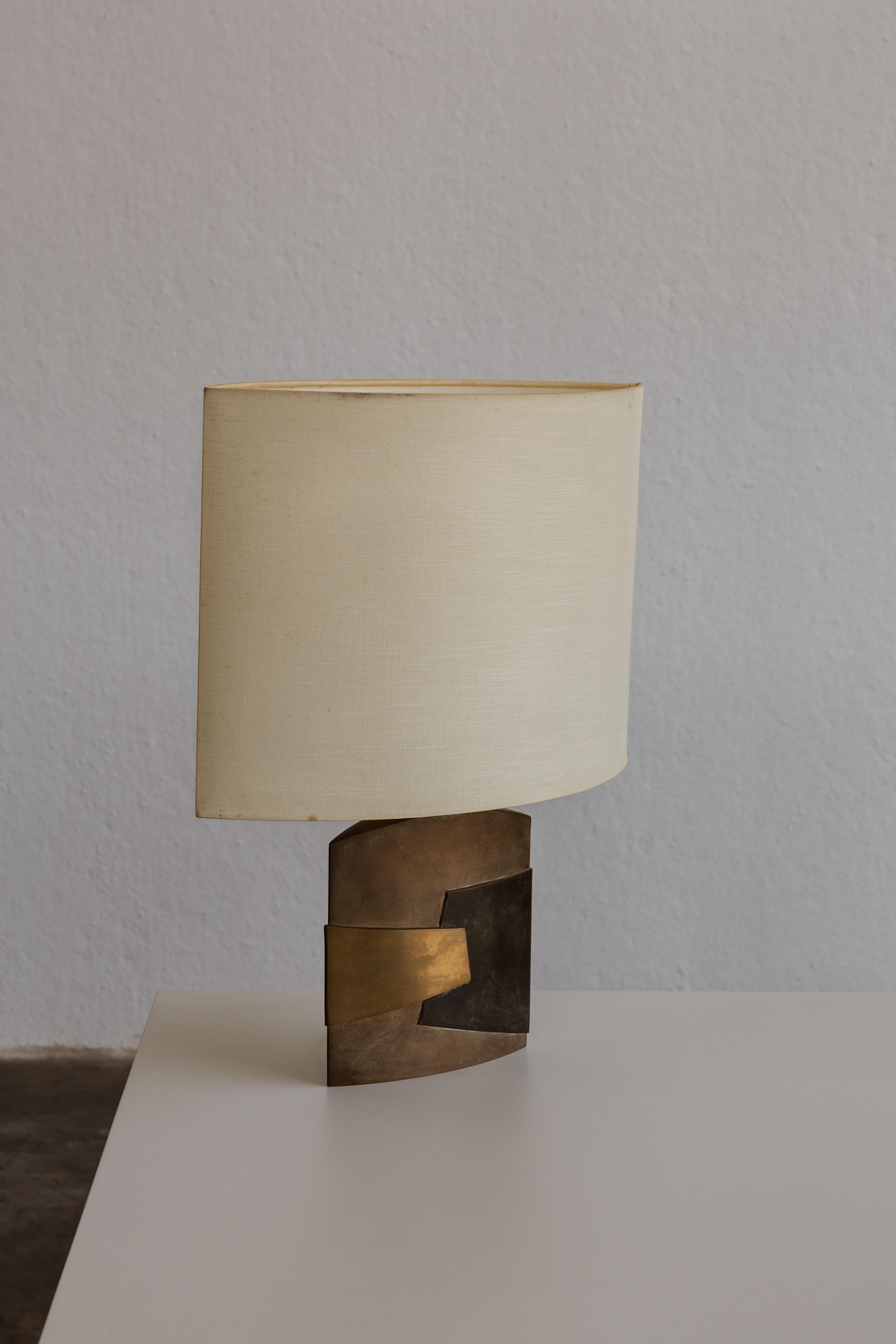 Esa Fedrigolli table lamp for Spirale Arte, bronze, fabric and steel, 1970s.

The Elsa Fedrigolli table lamp exemplifies the modernist style, a forerunner that blends artistry with architectural elegance. This sail-shaped silhouette luminaire is