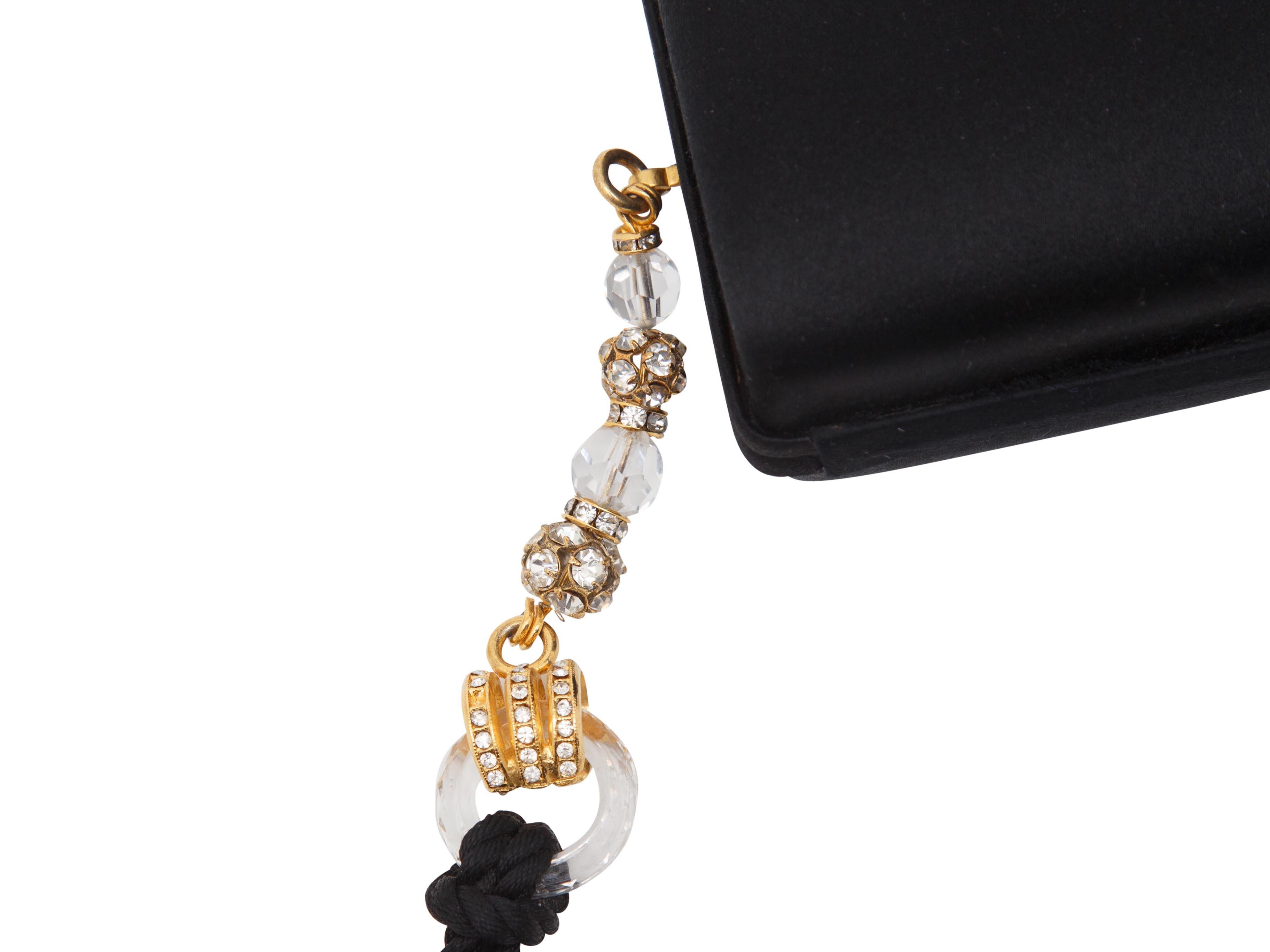Product details:  Vintage black satin evening clutch by Escada.  Accented with an oversized tassel.  Top crystal-accented push-lock closure.  Lined interior.  Goldtone hardware.  5.5