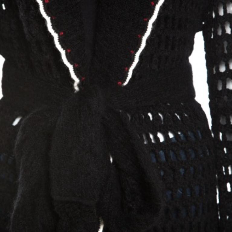 Questo delizioso cardigan è stato disegnato da Escada in una combinazione di tessuti pregiati. Presenta un'applicazione floreale multicolore e una cintura da annodare sul davanti. Con maniche lunghe, questa creazione nera è caratterizzata da