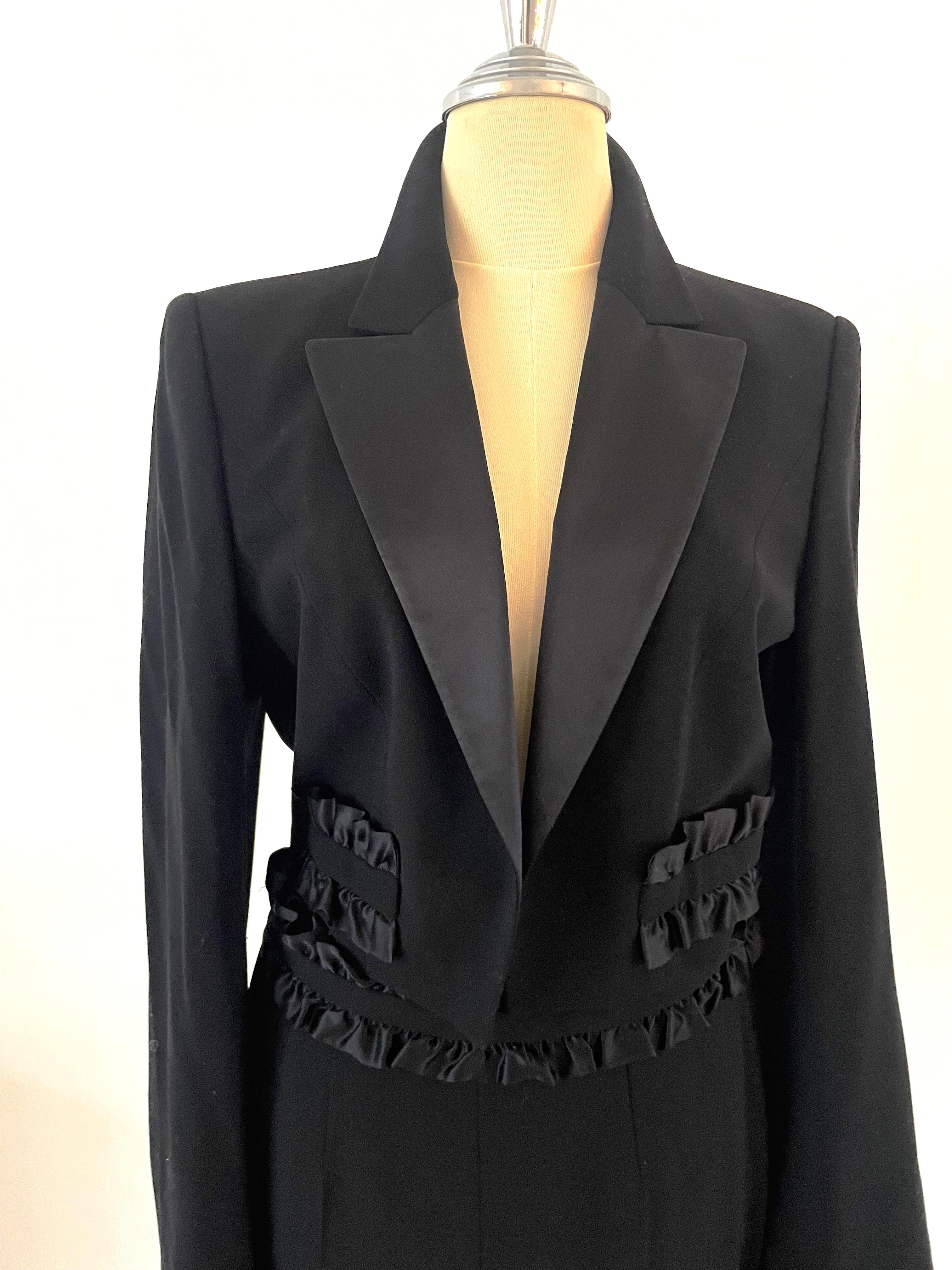 This vintage 90s Escada black suit made from 96% wool with silk ruffles, is a classic piece that highlights the brand’s attention to luxurious fabrics and unique detailing. Worn by a topmodel.
The silk ruffles add a distinct, elegant touch to the