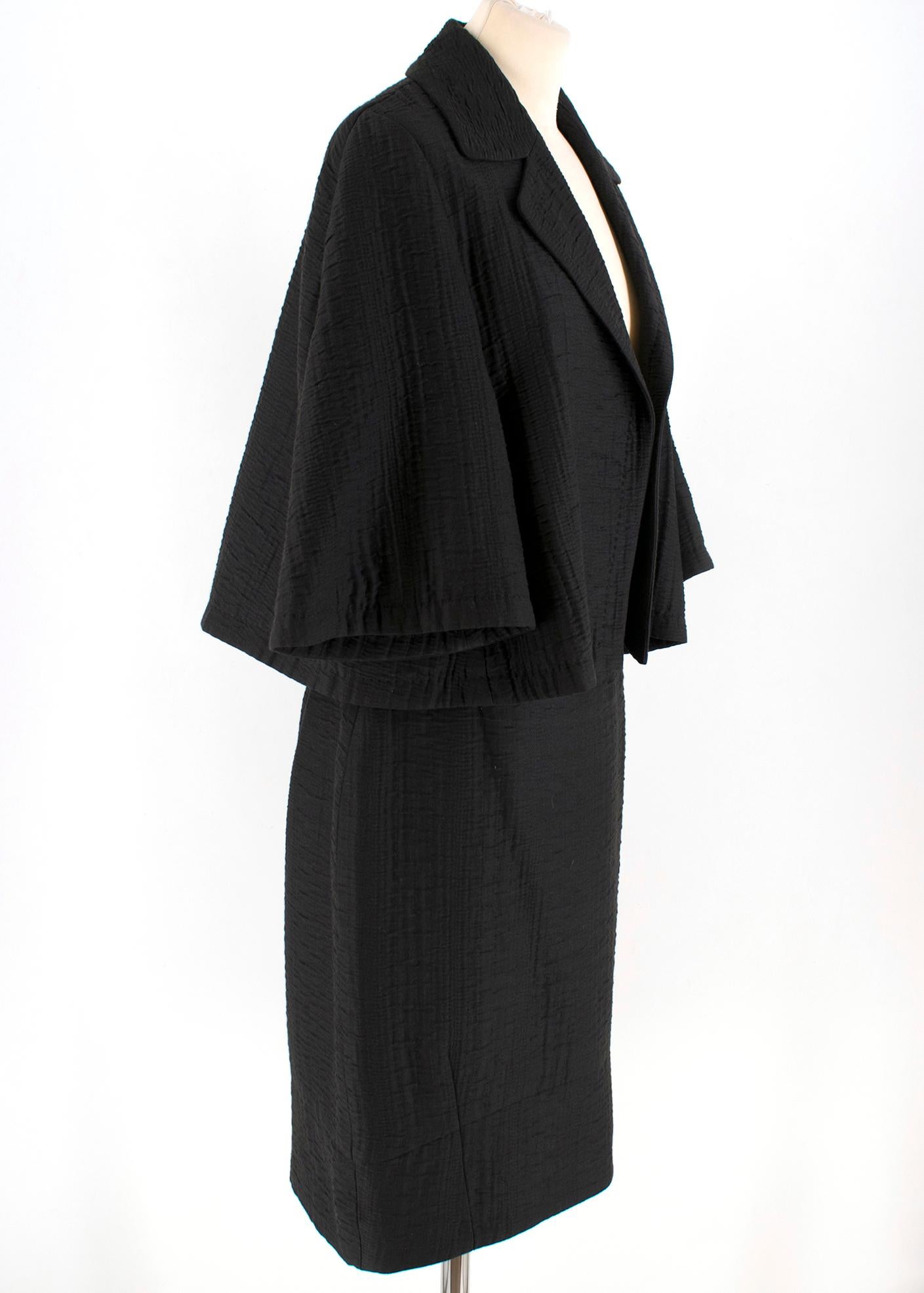 Escada Black Textured Jacket & Skirt

Blazer Jacket:

- This finely textured blazer jacket is a cropped piece with flared short sleeves with wide notched lapels
- NO button fastening (open)

Skirt:

- Tube shaped skirt, 
- Black cotton textured