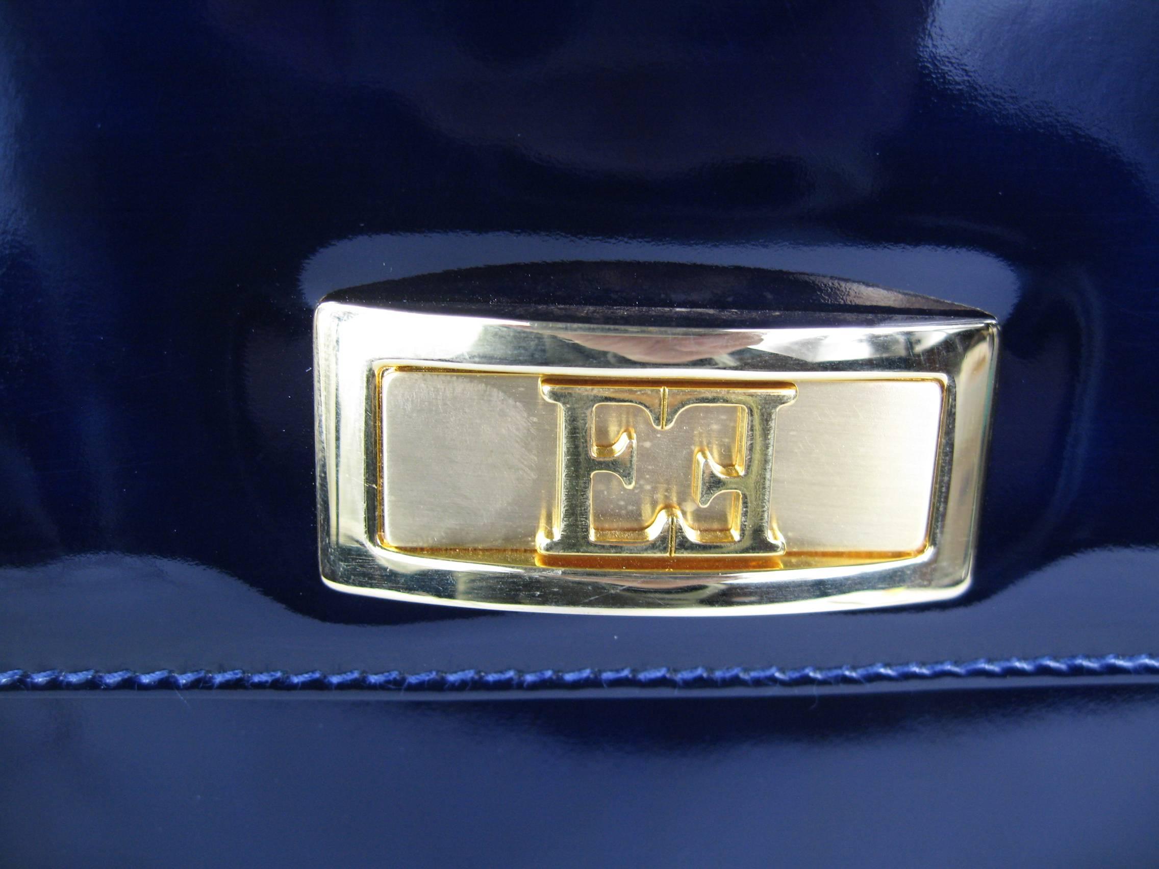 Deep Blue Escada Leather Kelly handbag. Still has original Price tags attached. Measures 11.5 in wide at the bottom x 9 in high x 2-7/8 in deep with a 13.5 in drop on leather shoulder strap. Magnetic closure. Gold Tone hardware and feet and Zippered