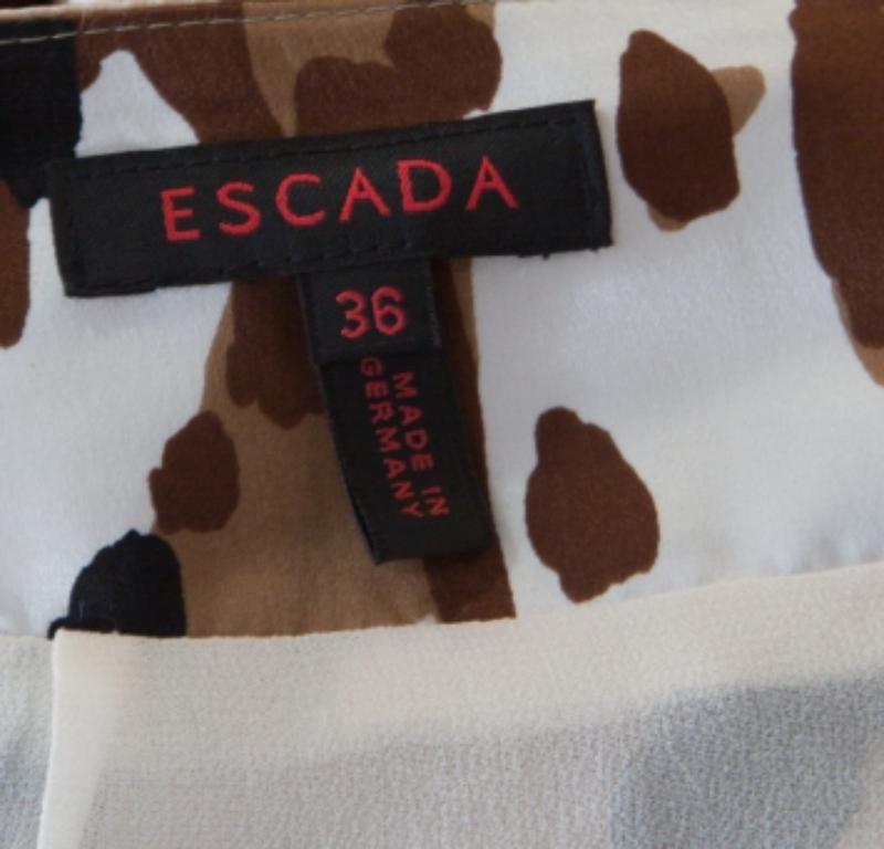 Splendida nelle forme e di grande fascino, questa gonna è della casa Escada. È realizzato in seta di qualità e disegnato con stampe mimetiche astratte. Questa creazione sarà perfetta con un top a tinta unita e dei sandali con cinturino.