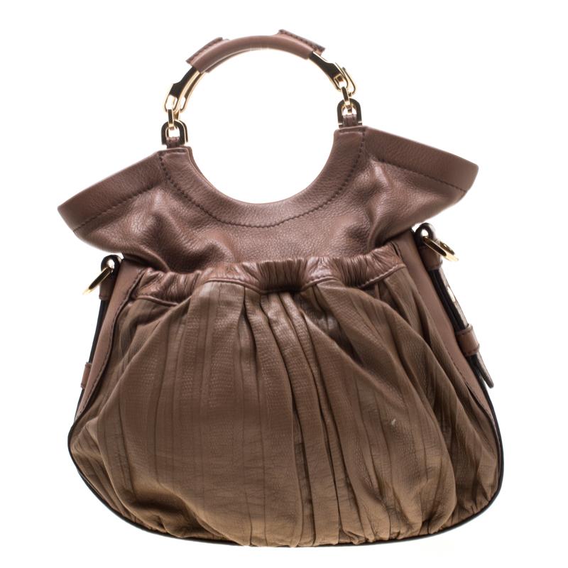 This stylish hobo from Escada is a lovely piece to carry every day to work and will look equally great with your casual outfits. It has a pleated exterior with slip pockets both at the front and back along with two top handles, and a gold-tone logo