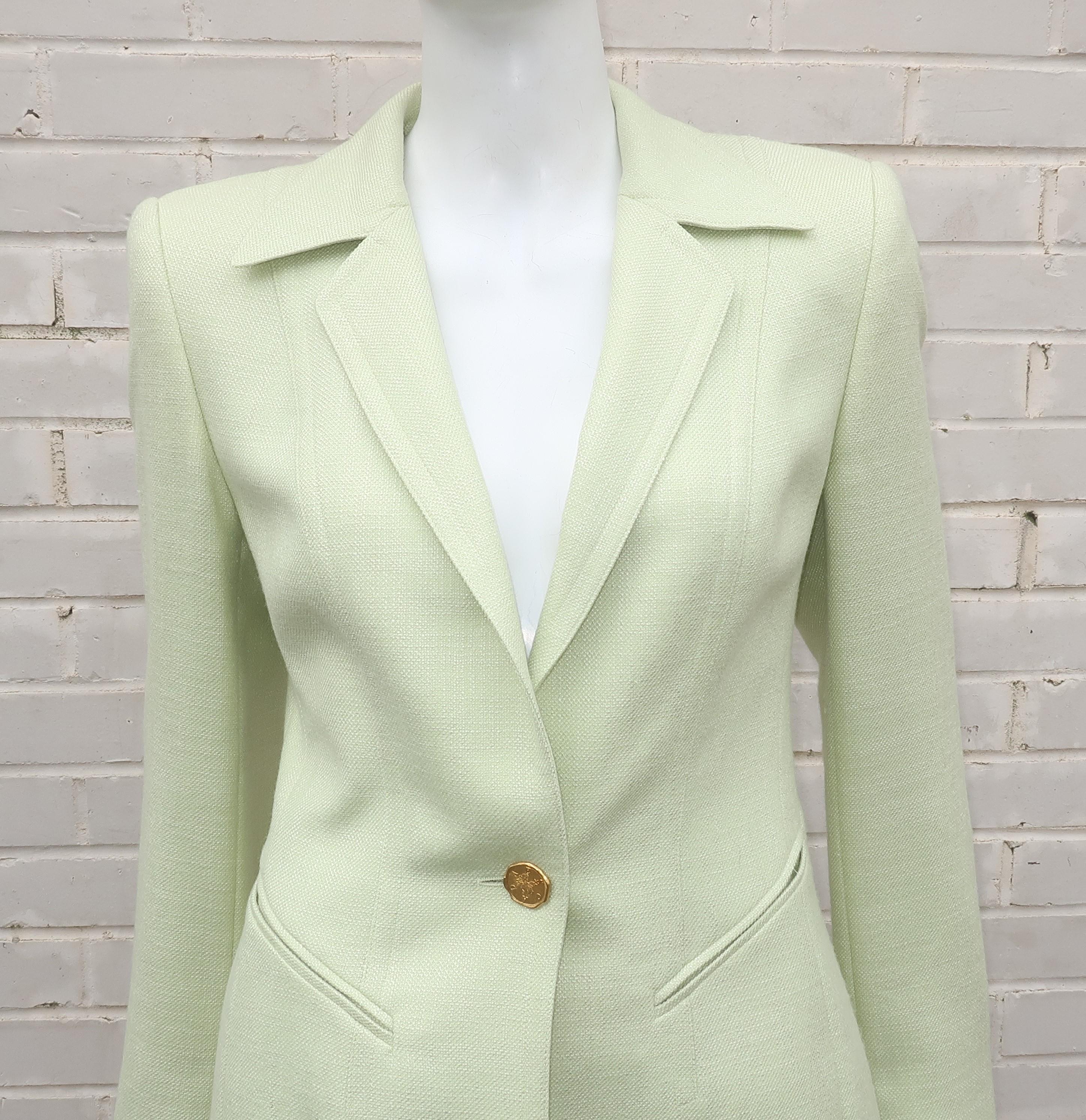 Escada creates a classically beautiful skirt suit fabricated from a wool and silk blended fabric in a celery green hue.  The jacket features structured shoulders, front pockets and detailed cuffs with gold tone logo buttons replicating ancient