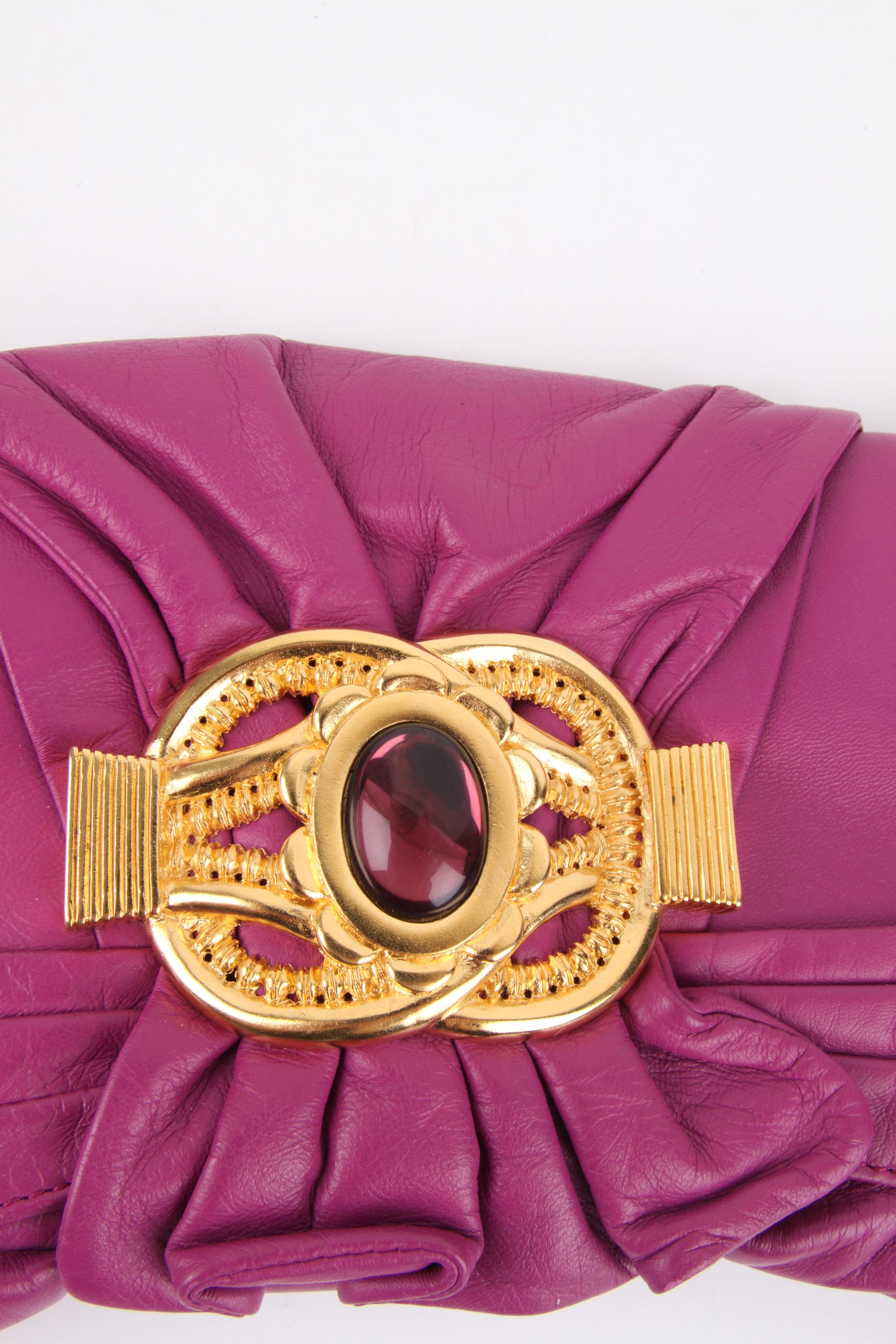 Outstanding clutch by Escada in purple leather.

On the flap a large gold-tone ornament and pleated leather, concealed magnetic closure underneath.

Lining in off-white leather, one small flat pocket.

In very good condition, maybe worn once or