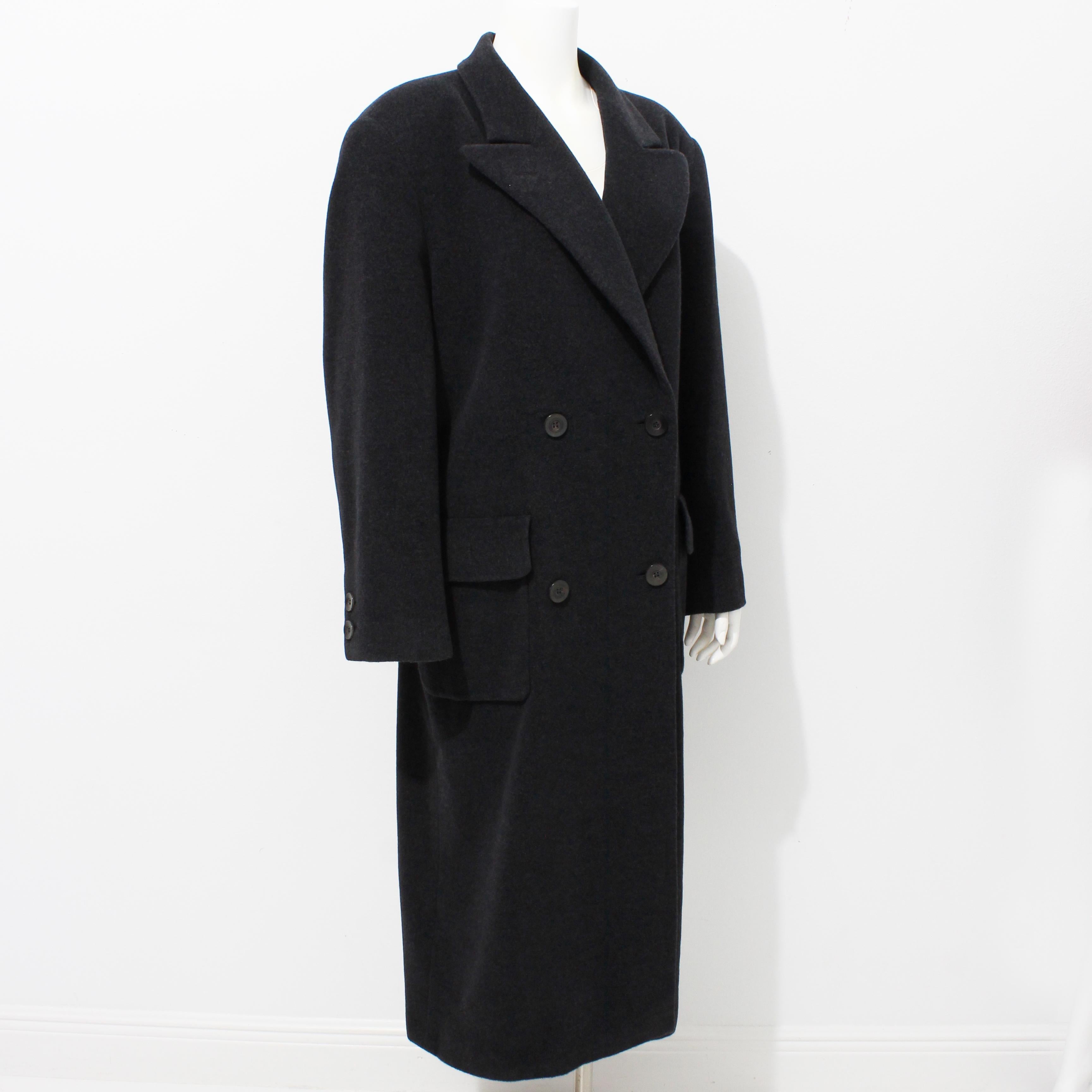 Authentic, preowned, vintage Escada coat, likely made in the 90s. Made from 100% Pure New Wool in a charcoal gray hue, it features double-breasted construction with flap pockets at each hip and a faux belt in back.   

An iconic style and