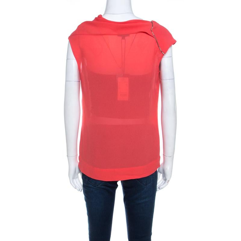 This sleeveless Neslisah top from Escada is liked for its sophisticated elegance. Designed in a coral orange hue with crystal embellishments, this top features a simple silhouette and cowl neckline. Wear it with a pair of jeggings and
