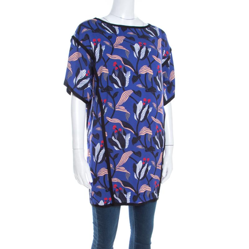 Cut to a stylish silhouette with short sleeves, this Escada Naternia tunic top is perfect for your casual dos. It flaunts a blue hue with a floral print all over. Crafted from a silk blend, the top will work best with regular jeans, high heels, and