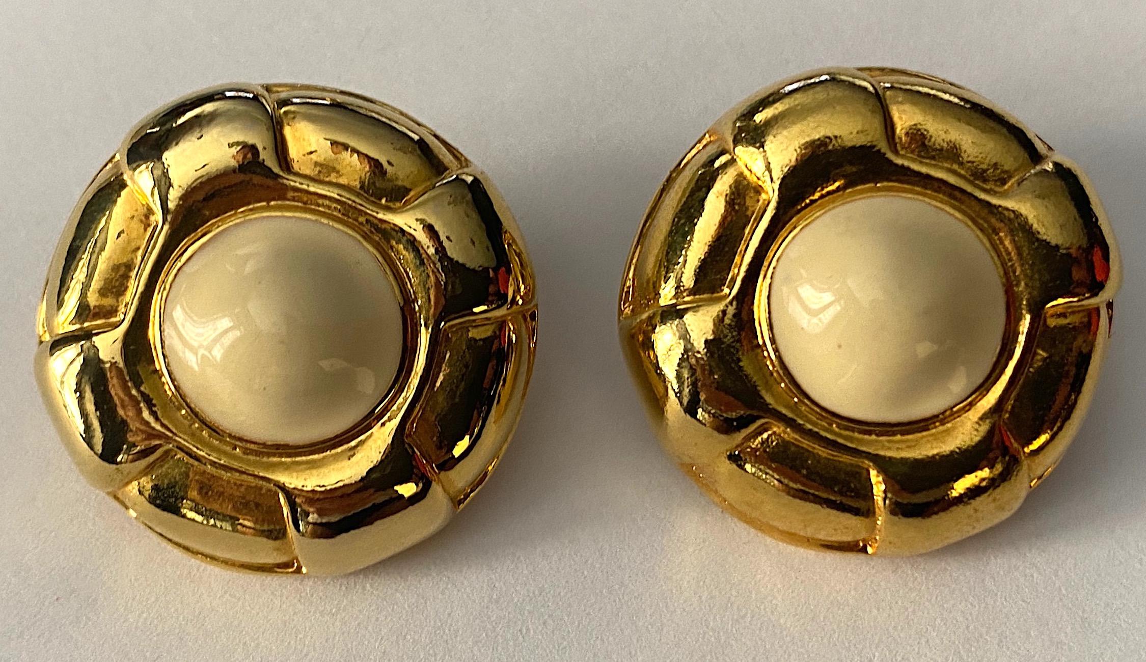 A very lovely pair of Escada button style clip earrings circa 1980. Each earring measures 1.19 inches in diameter and .38 of an inch deep, not including the clip back. The centers have a .5 inch diameter of ivory enamel. Each earring has an oval