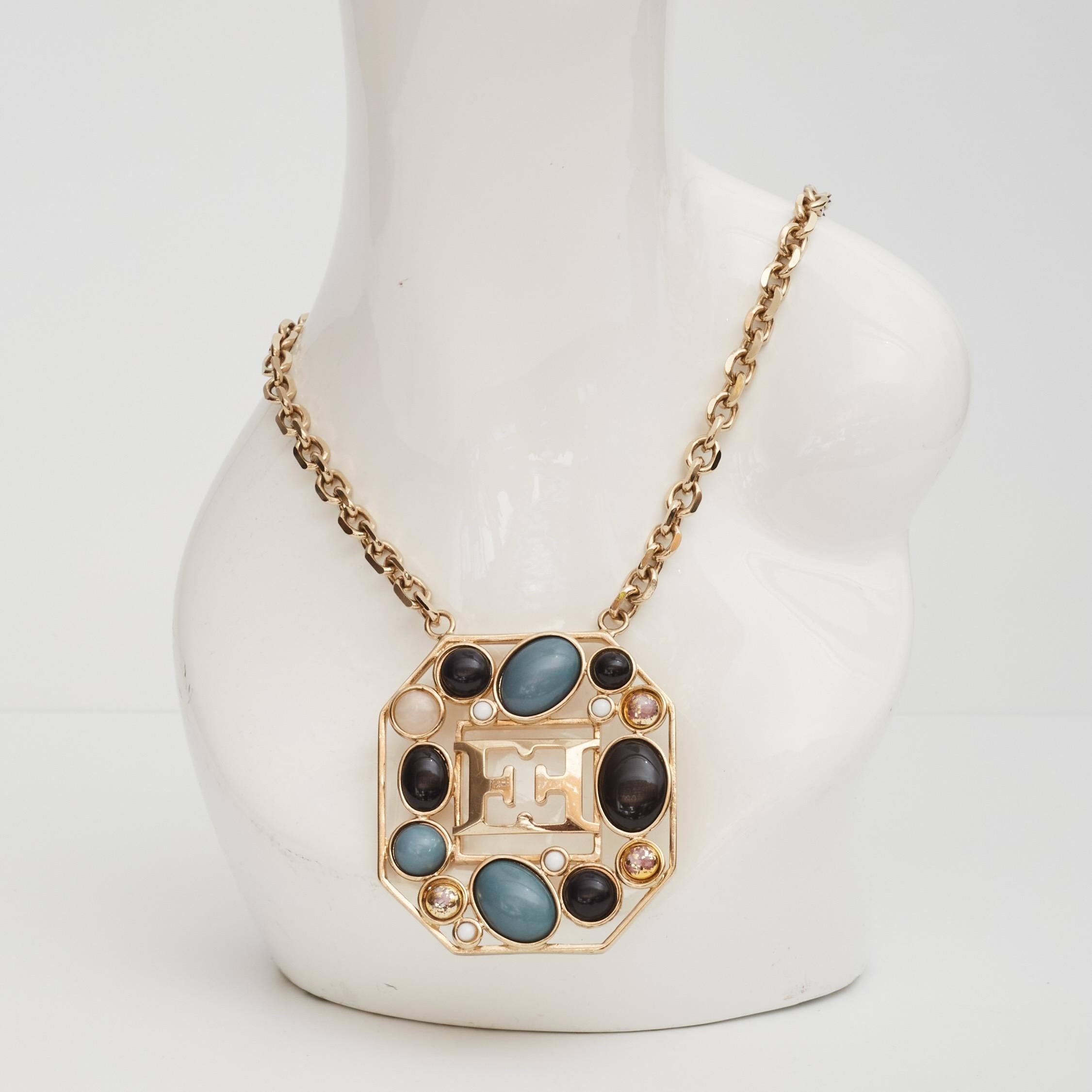 Color: Gold tone chain. Gold pendant with white, turquoise & black glass embellishments
Material: metal and glass
Year: Circa 2000s

Measures:
Chain 34”
Pendant drop: 3.5” x 3”

Comes with: Leather box
Condition: Very good. Light scratches to
