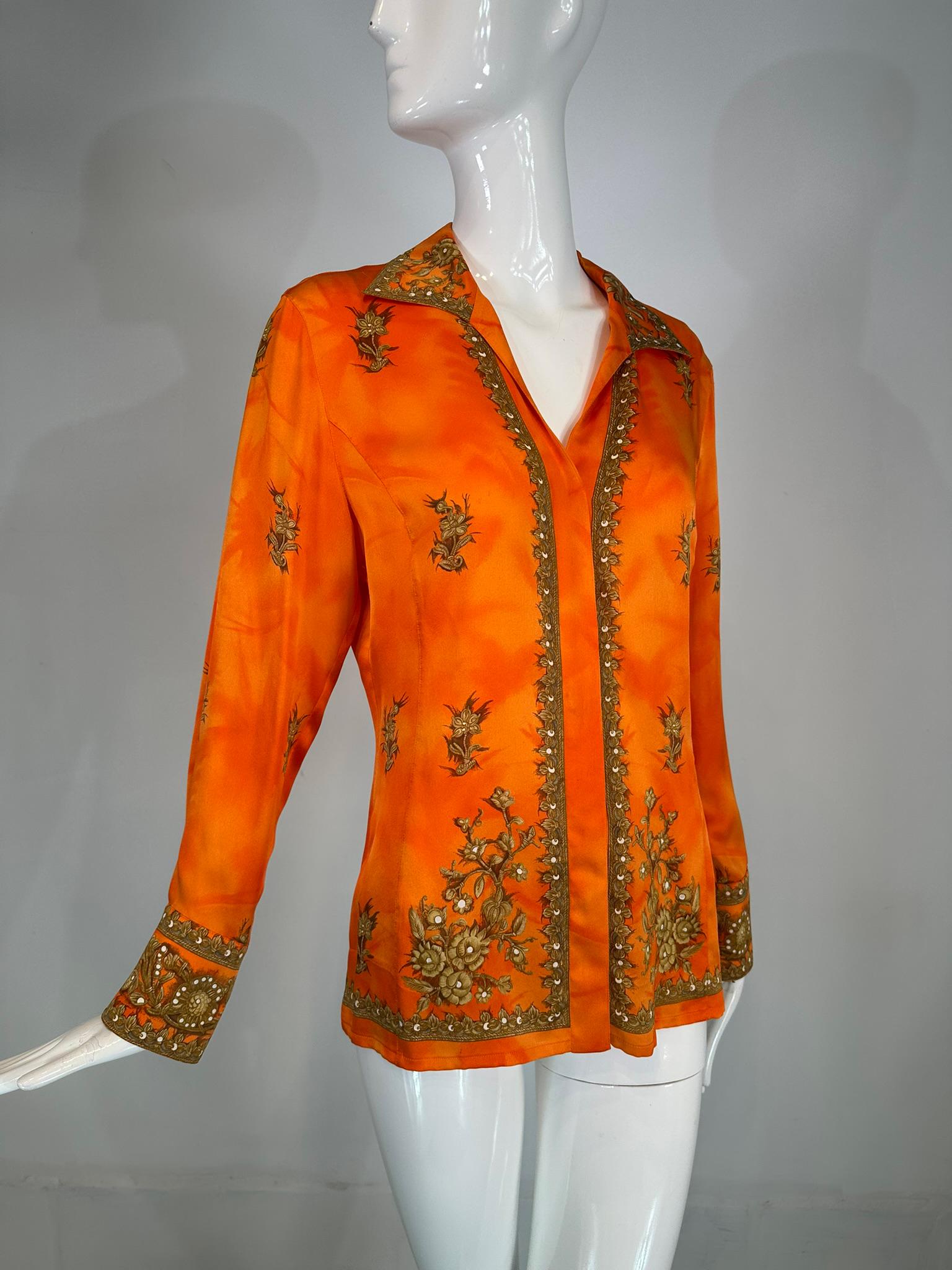 Escada langärmelige orange-goldene Seidenbluse mit Prinzessnähten und floralen Bordüren. Die Bluse hat einen interessanten, orangefarbenen Grund mit goldenen Nuancen. Die Ränder der Bluse haben einen goldenen Blumendruck mit weißen Punkten, die