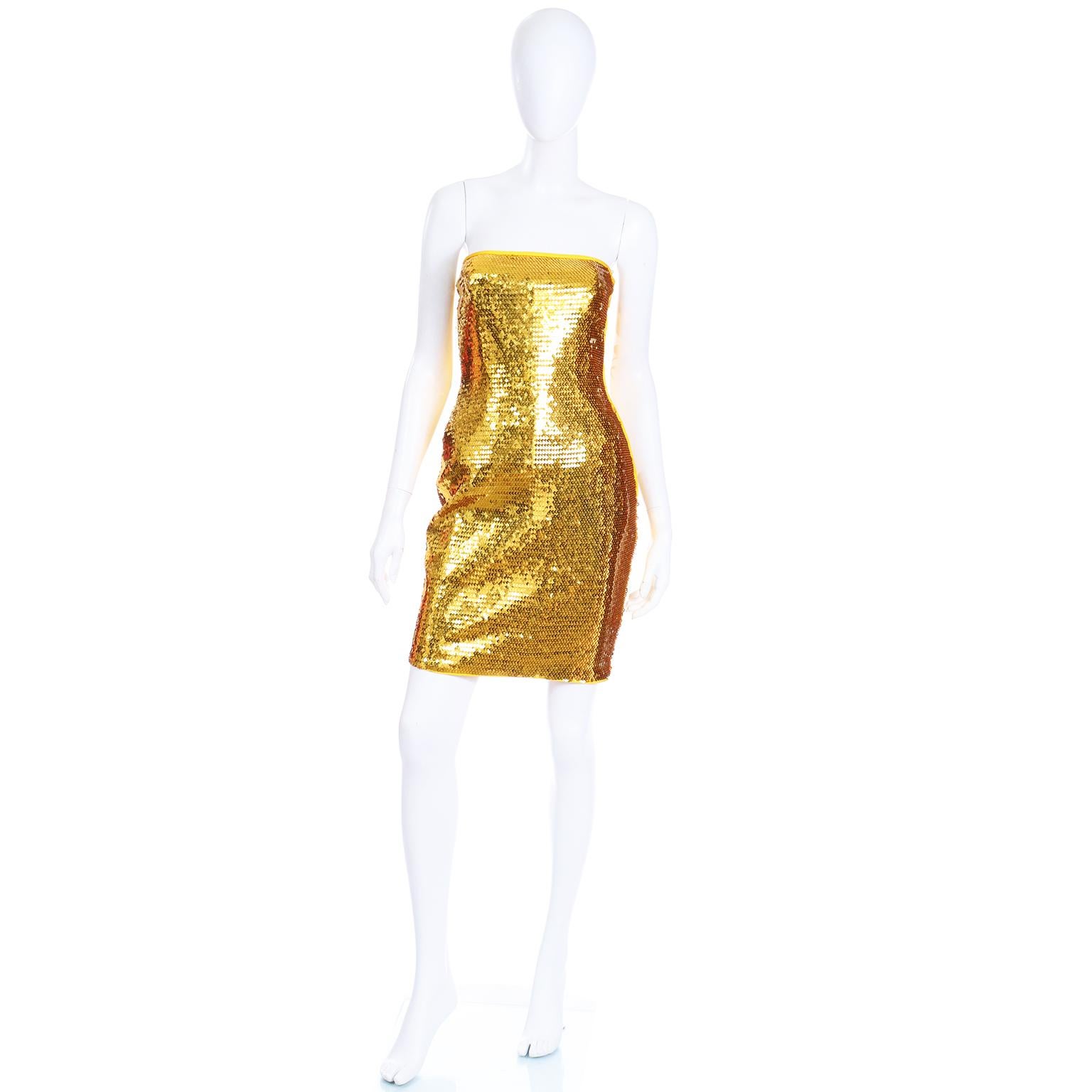 This is a stunning vintage Escada Margaretha Ley strapless evening dress that appears to have never been worn. The dress is fully covered in bright gold paillettes and has yellow gold piping around the top and up the sides. There is a built in slip