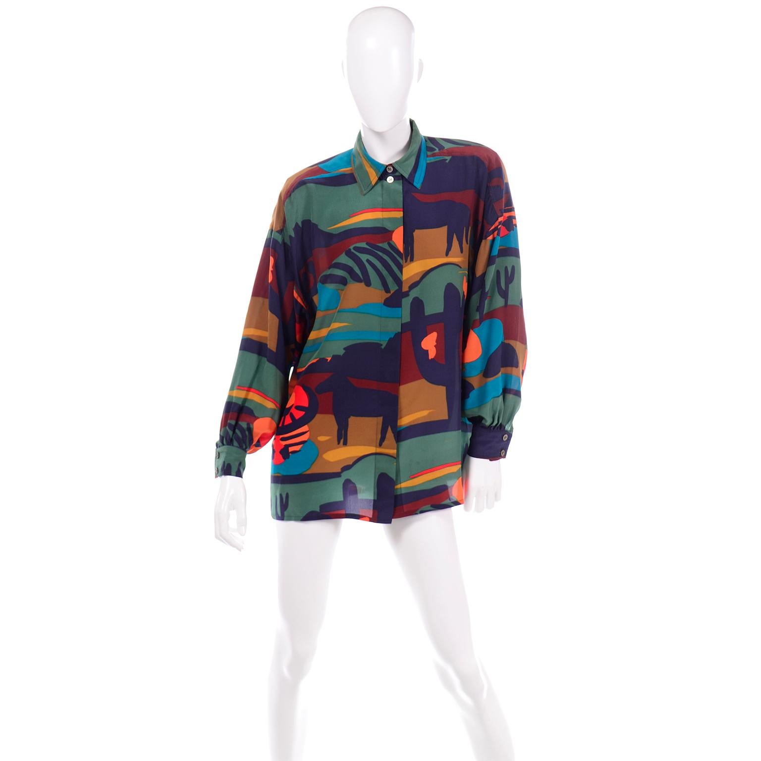 This vintage 1980's Margaretha Ley Escada long sleeve blouse is in a Western theme novelty print that resembles painted brush strokes. The top is in shades of navy, teal, orange, red, mustard, marigold, and burgundy. The placket of the shirt hides