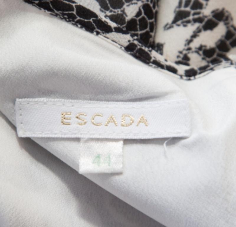 Questo abito monocromatico è di Escada. L'abito in seta conquista con il suo design femminile, lo scollo a barca e la lunghezza midi. Presenta stampe in pizzo e un orlo a balze che perfeziona la silhouette altrimenti semplice.