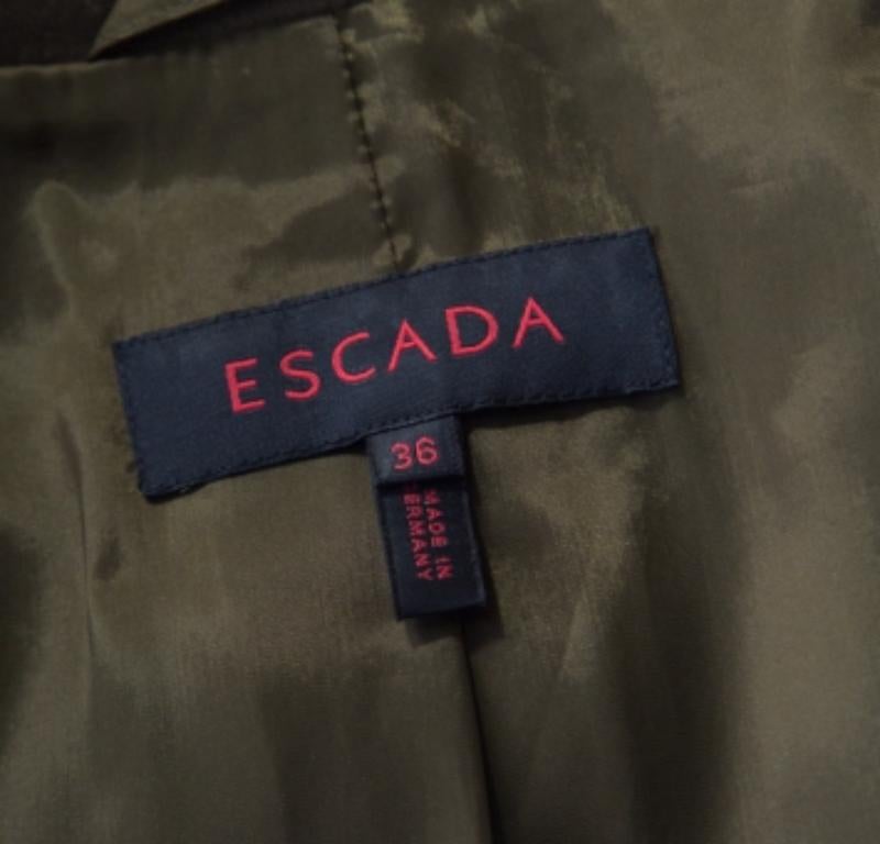 Dieser wunderschöne und sehr moderne Blazer von Escada lässt andere bewundernd nicken. Der fabelhafte olivgrüne Blazer ist aus hochwertigen MATERIALEN gefertigt und hat eine strukturierte Silhouette. Er hat ein stilvolles Revers, lange Ärmel und