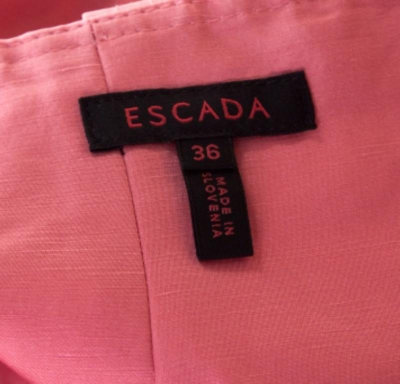 I nostri cuori corrono per questa gonna incantata di Escada. È realizzato su misura in lino e seta e presenta una cintura in vita e un orlo che cade sotto le ginocchia. Puoi abbinarlo a una camicetta bianca e a dei sandali rosa bubblegum.