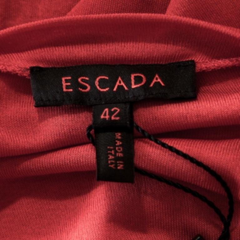 Devi assolutamente mettere le mani su questa deliziosa creazione di Escada. Il top rosso è cucito perfettamente e presenta maniche lunghe e trasparenti e un incrocio sul davanti. Può essere abbinato a jeans o pantaloni e a un paio di décolleté