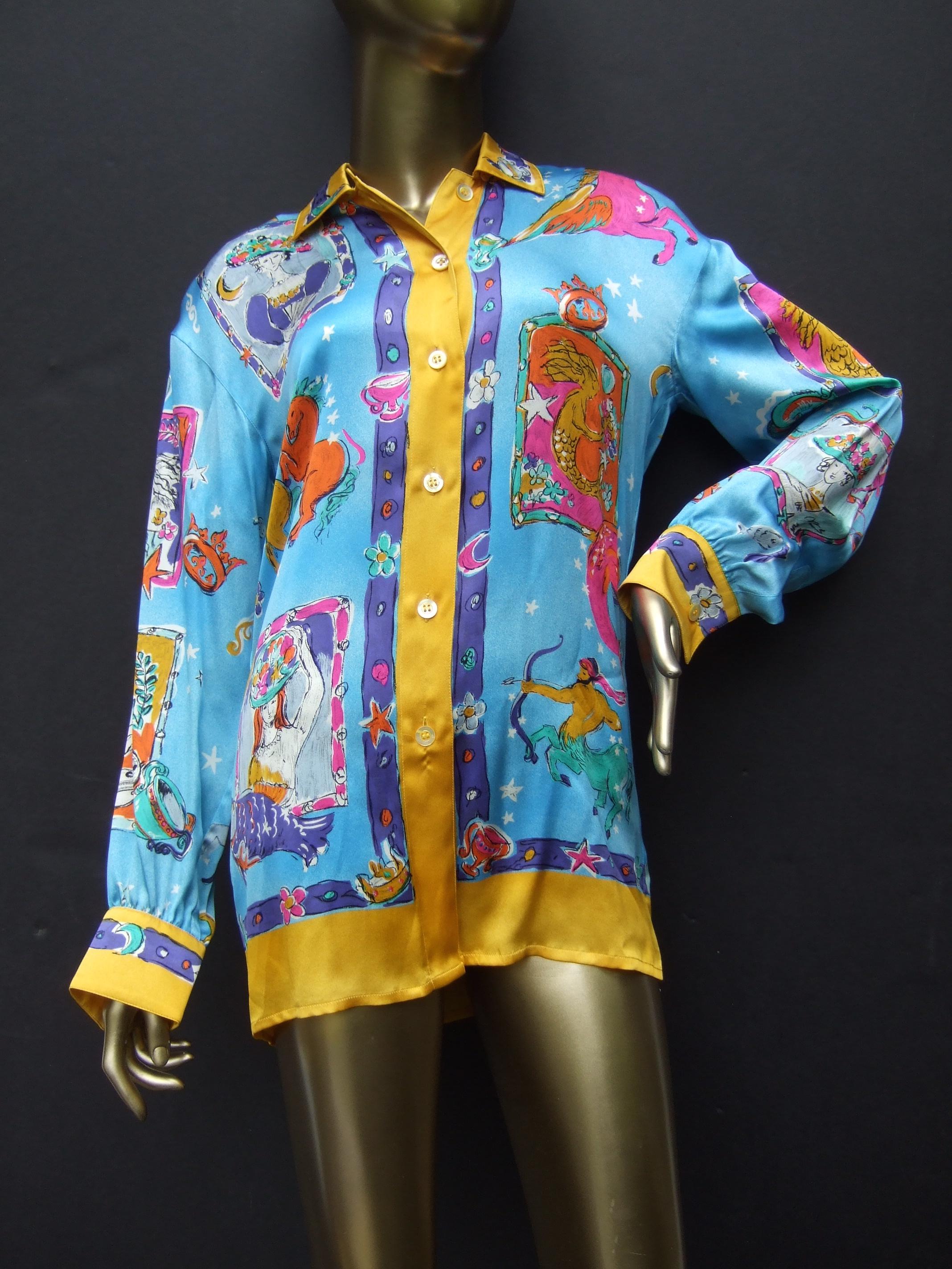 Escada Silk charmeuse astrological zodiac graphic print blouse. New-Vintage Size 34
The stylish silk blouse is illustrated with a collage of vibrant graphic designs; illuminated against a turquoise aqua-blue background that represents the sky with