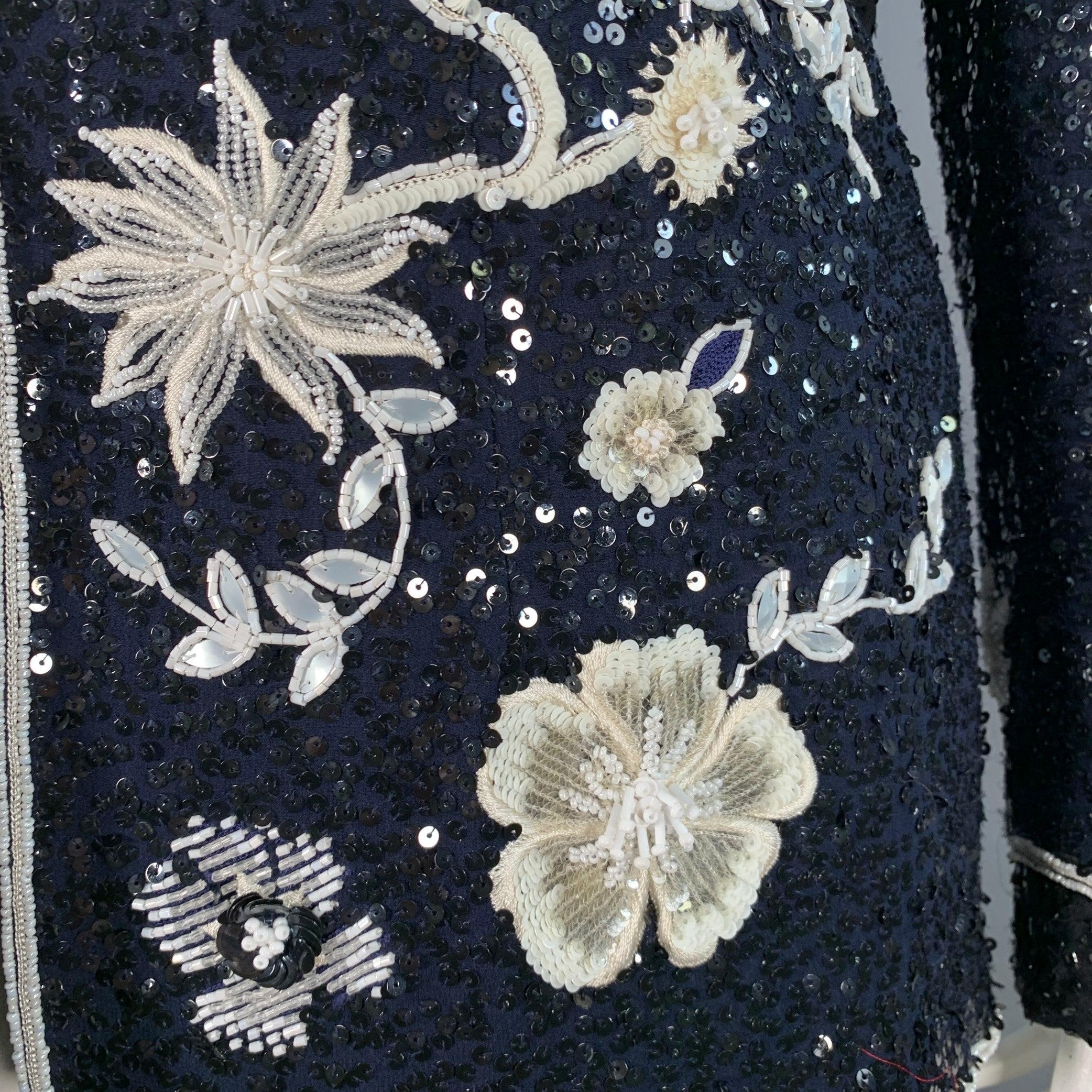 Blazer Escada
in tessuto blu scuro con un disegno floreale di paillettes e perline in bianco e nero, risvolto con tacca e chiusura con gancio. Made in Germany.Ottime condizioni di usato. Lievi segni di usura nella bordatura. 

Contrassegnato:   DE