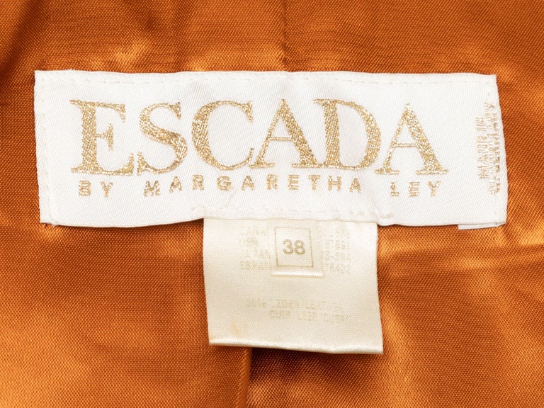 Product Details: Tan cropped leather jacket by Escada. Gold-tone hardware. Contrast stitching throughout. Crew neck. Grommet accents throughout. Dual hip pockets. Designer size 38. 36