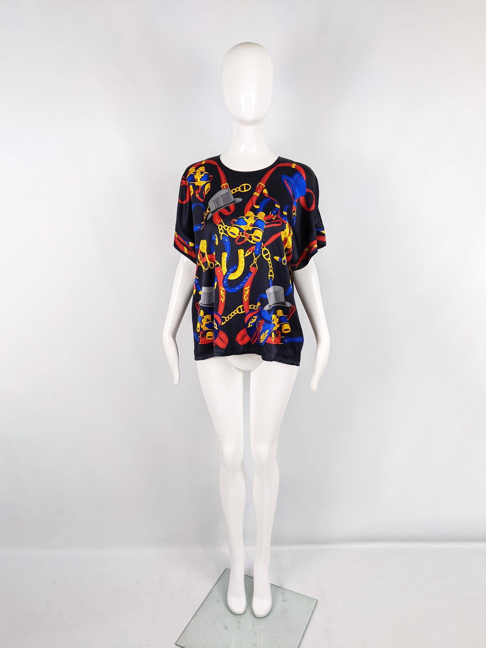 A cute vintage womens short sleeve blouse / shirt from the 80s by luxury fashion house, Escada. This top is made from a dark navy blue silk with a vibrant red and yellow coloured, equestrian themed baroque print. It has a boxy fit and a keyhole