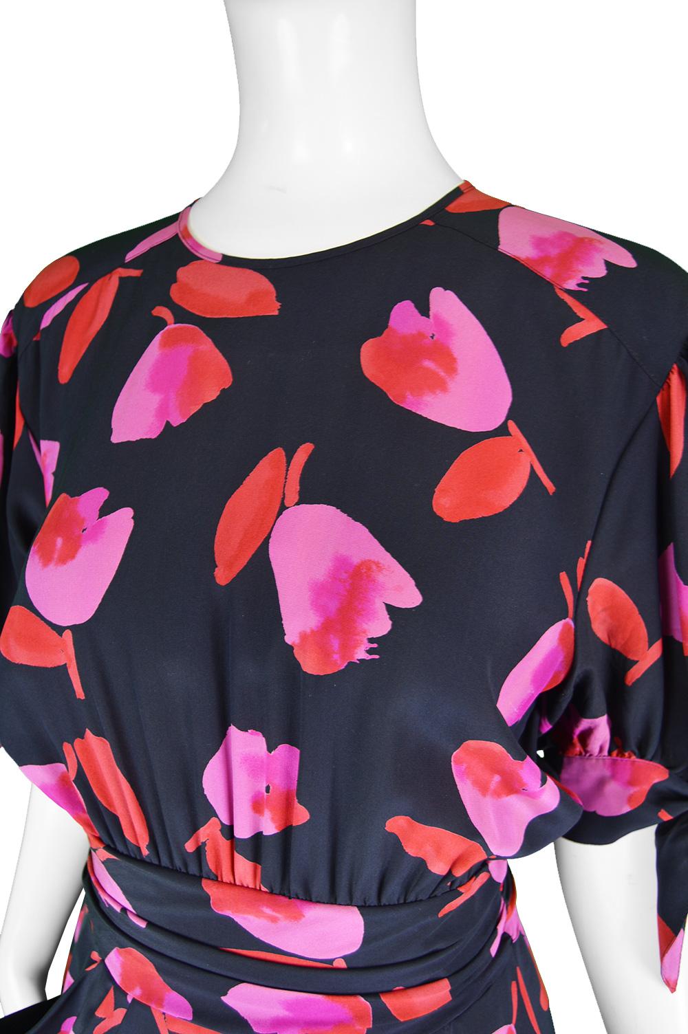 A fabulous vintage women's dress from the 90s by luxury German fashion house, Escada. In a black silk with a red and pink floral pattern throughout. the short puff sleeves have tie details on the end and the waist has a ruched effect. Fastening with