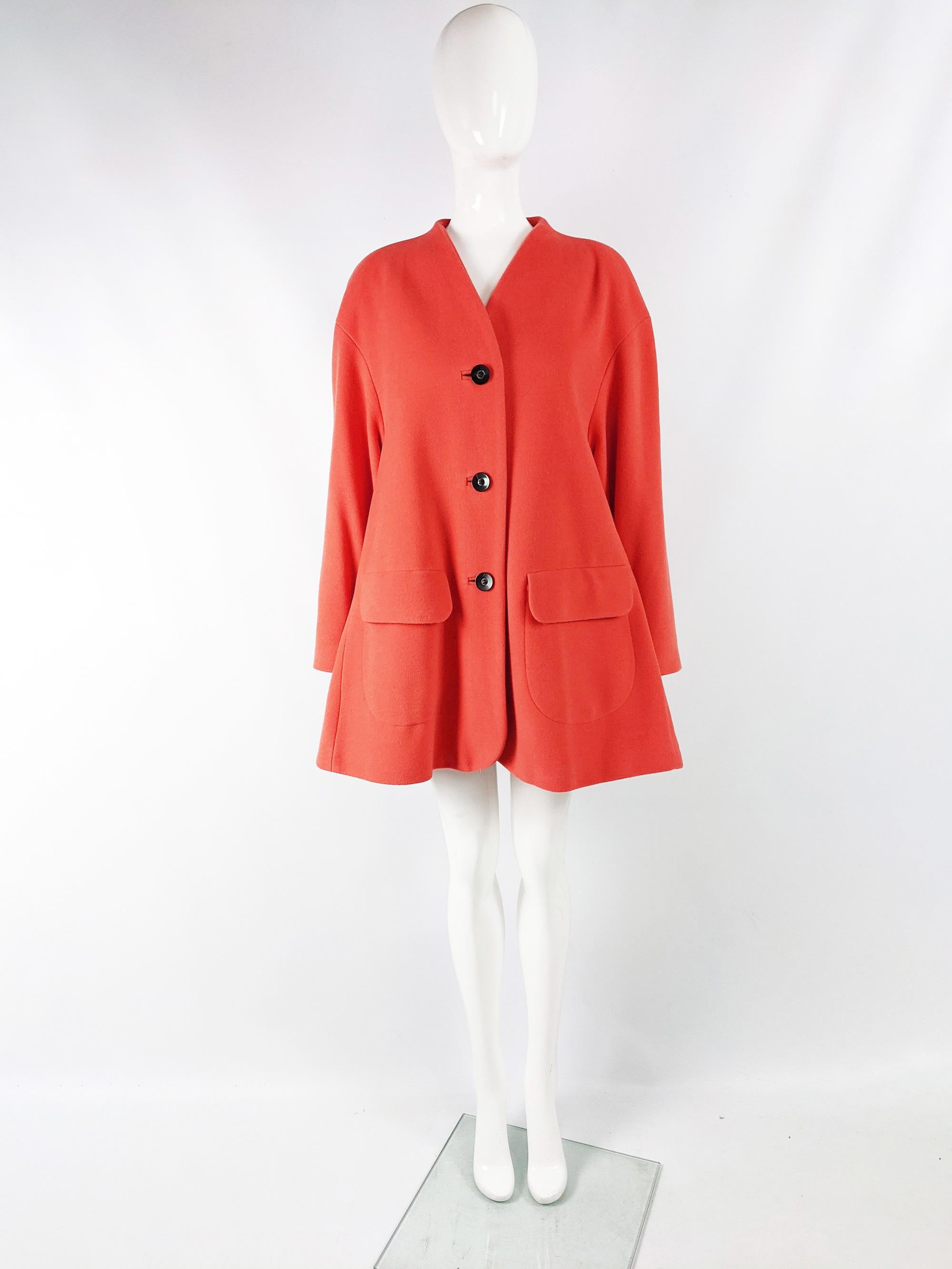 An incredible vintage womens swing coat from the 80s by designer fashion house, Escada. Made from a luxurious virgin wool, cashmere and angora blend orangish coral fabric. It has an amazing trapeze style silhouette that flares out further towards