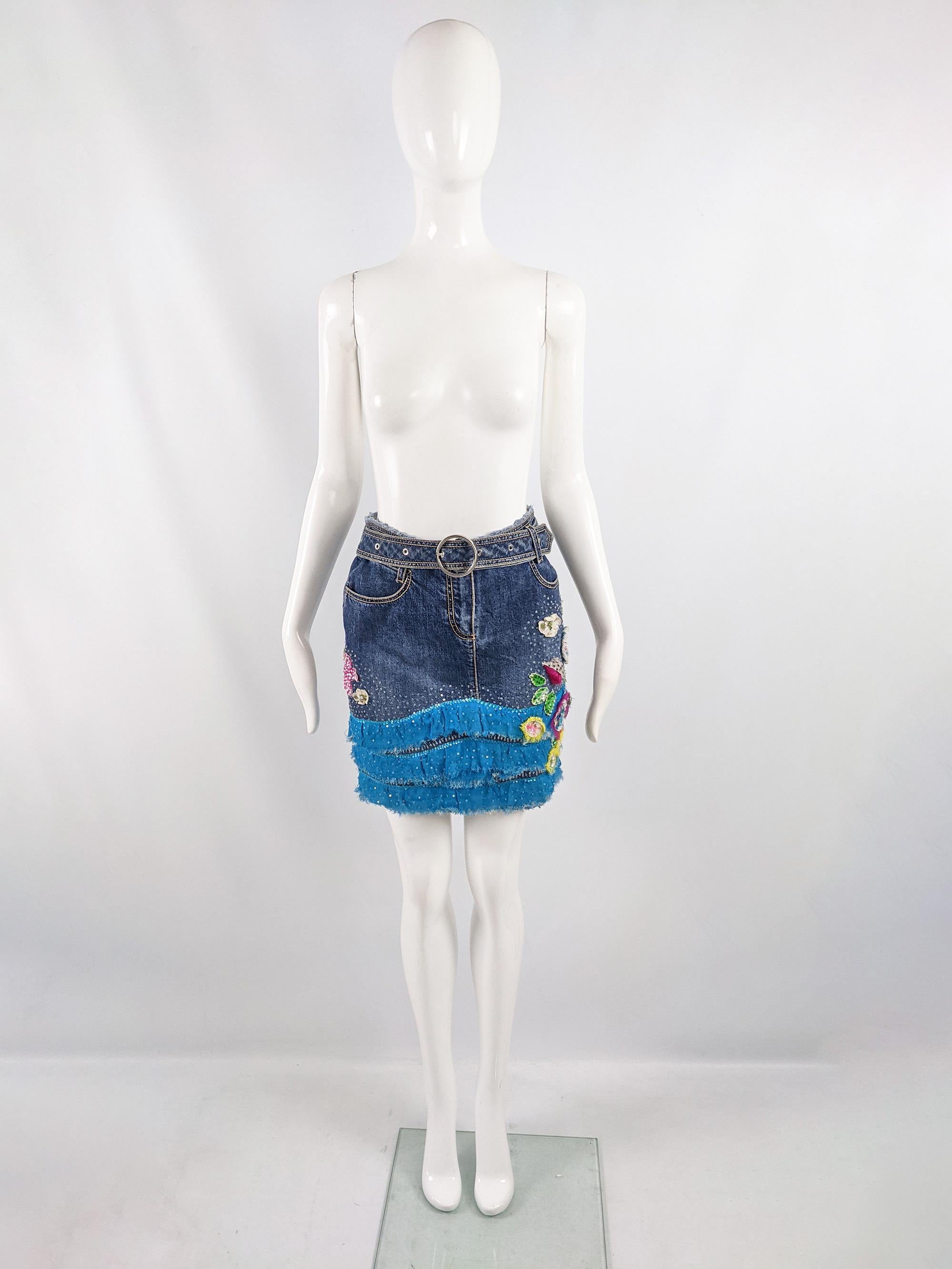 A cute vintage y2k womens mini skirt from the early 2000s by luxury fashion house, Escada. In a blue denim with a large matching belt with circular belt buckle, distressed chiffon tiered trim at the front and sequinned 3D floral appliqués. Perfect