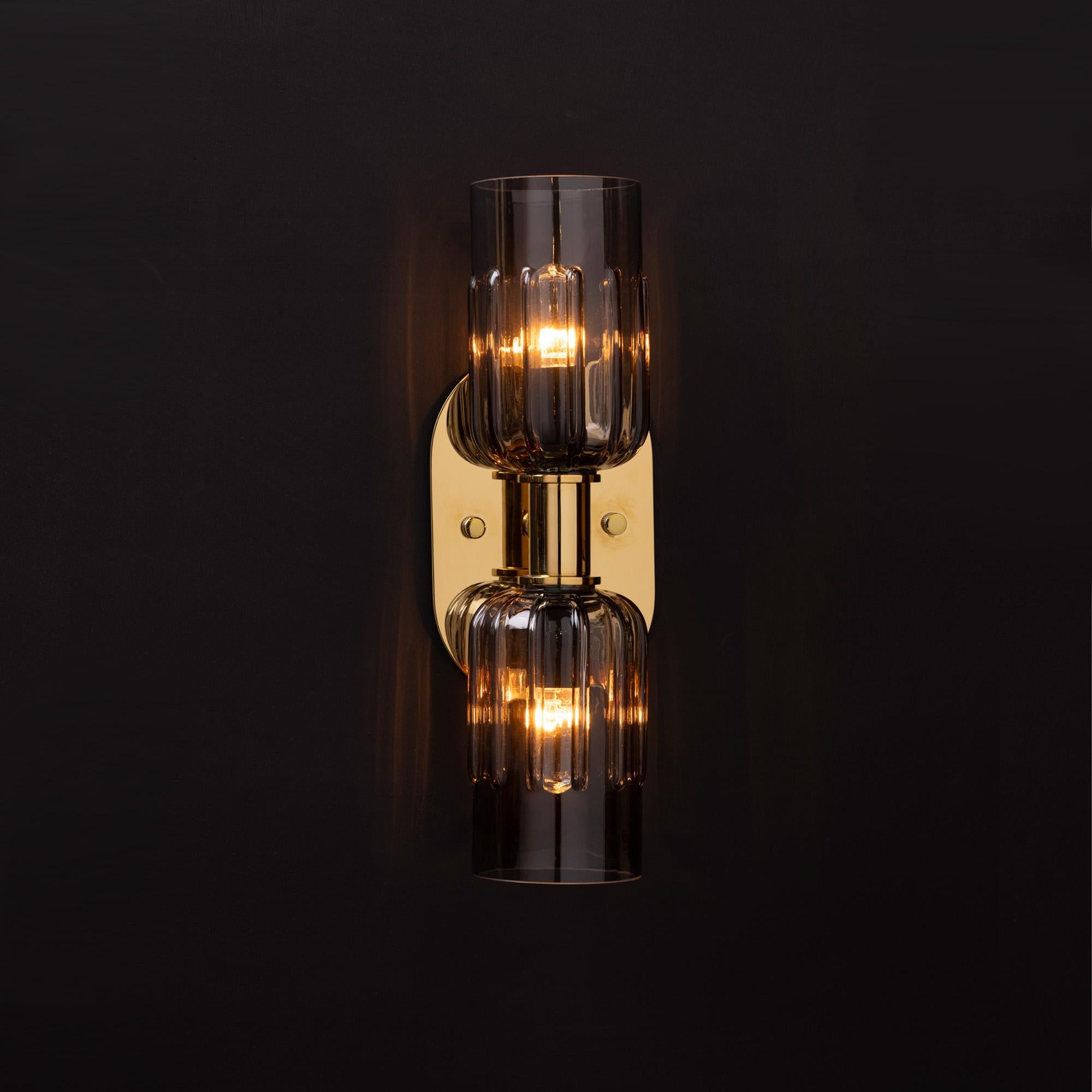 File di paralumi in vetro fumé soffiato a mano, con un'esclusiva cornice smerlata, si bilanciano su cornici architettoniche in ottone lucido o nichel.

Le collezioni di illuminazione LUXE sono realizzate a mano con i materiali più pregiati e