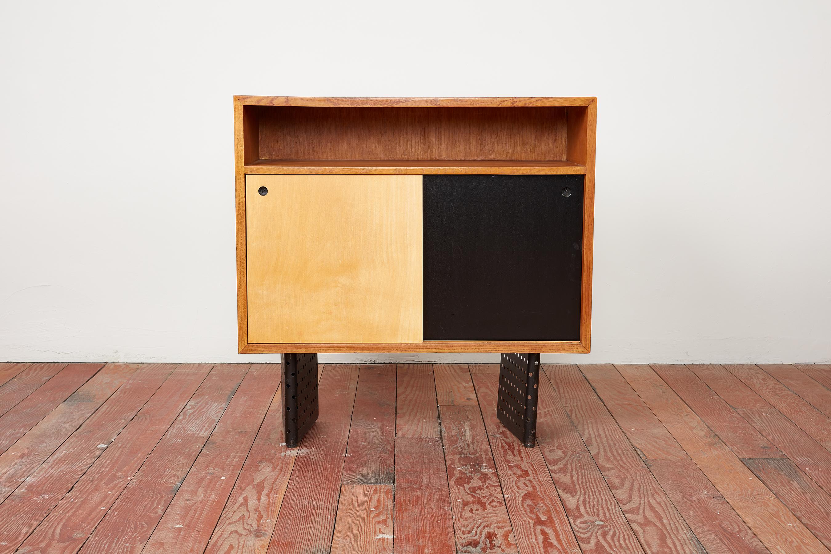 Rare Escande cabinet manufactured by Marcel Yvroud for Cité Universitaire, Antony, France circa 1954. 
Oak frames with sliding doors and open niche bookshelves
Signature perforated black metal legs 
Professionally refinished and restored to