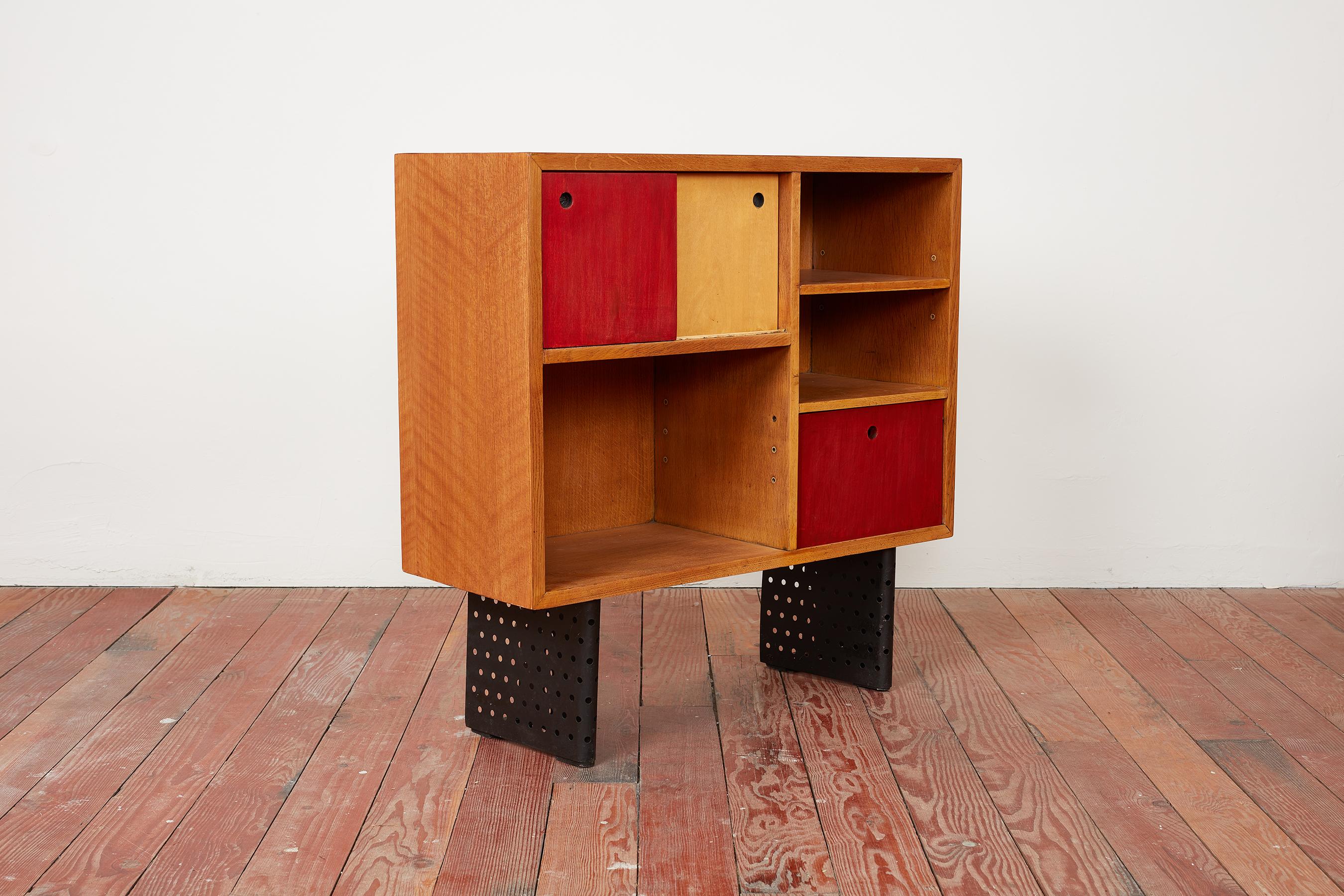Rare Escande cabinet manufactured by Marcel Yvroud for Cité Universitaire, Antony, France circa 1954. Oak frames with sliding doors and open niche bookshelves Signature perforated black metal legs Professionally refinished and restored to original